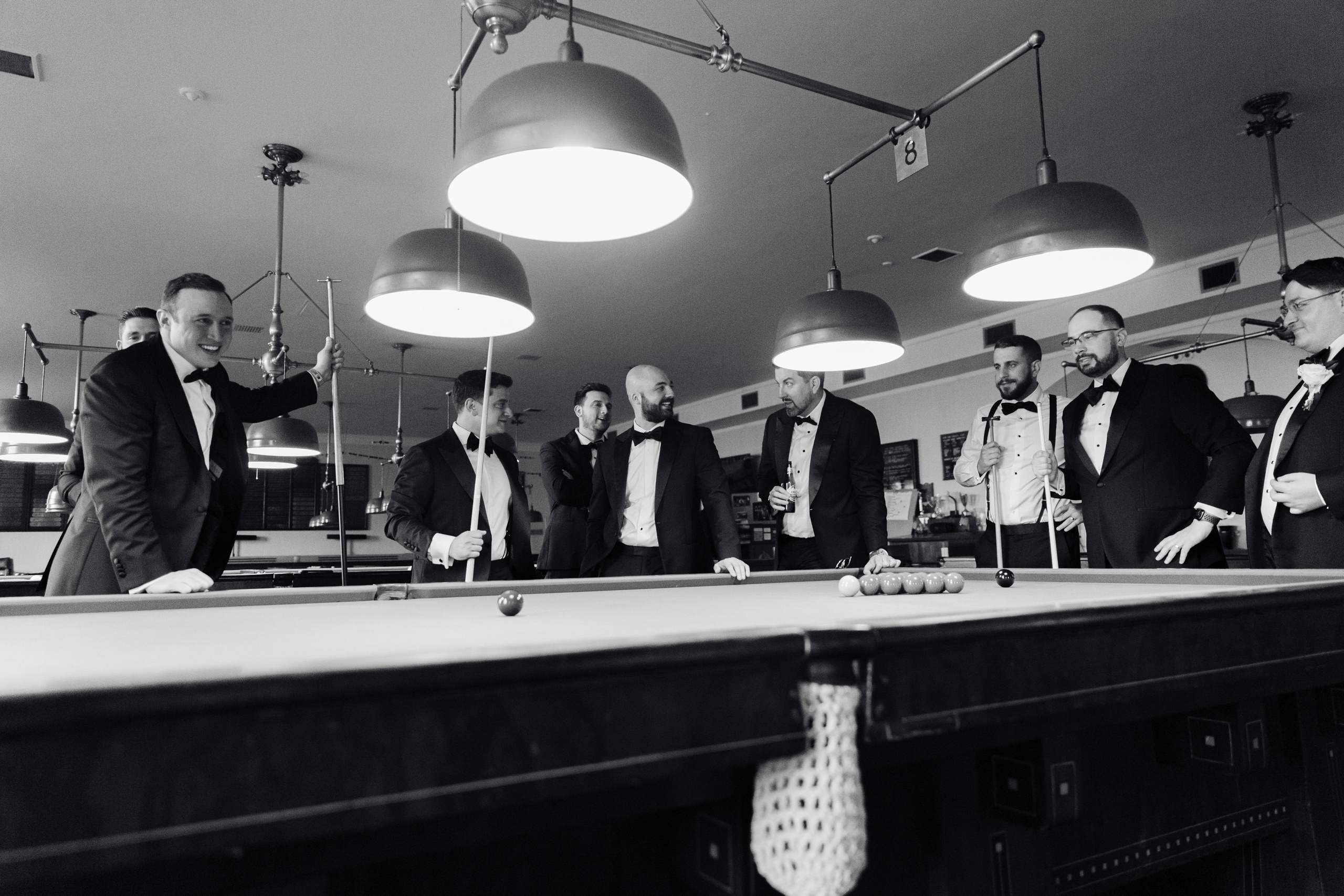 a group of men in tuxed suits playing pool