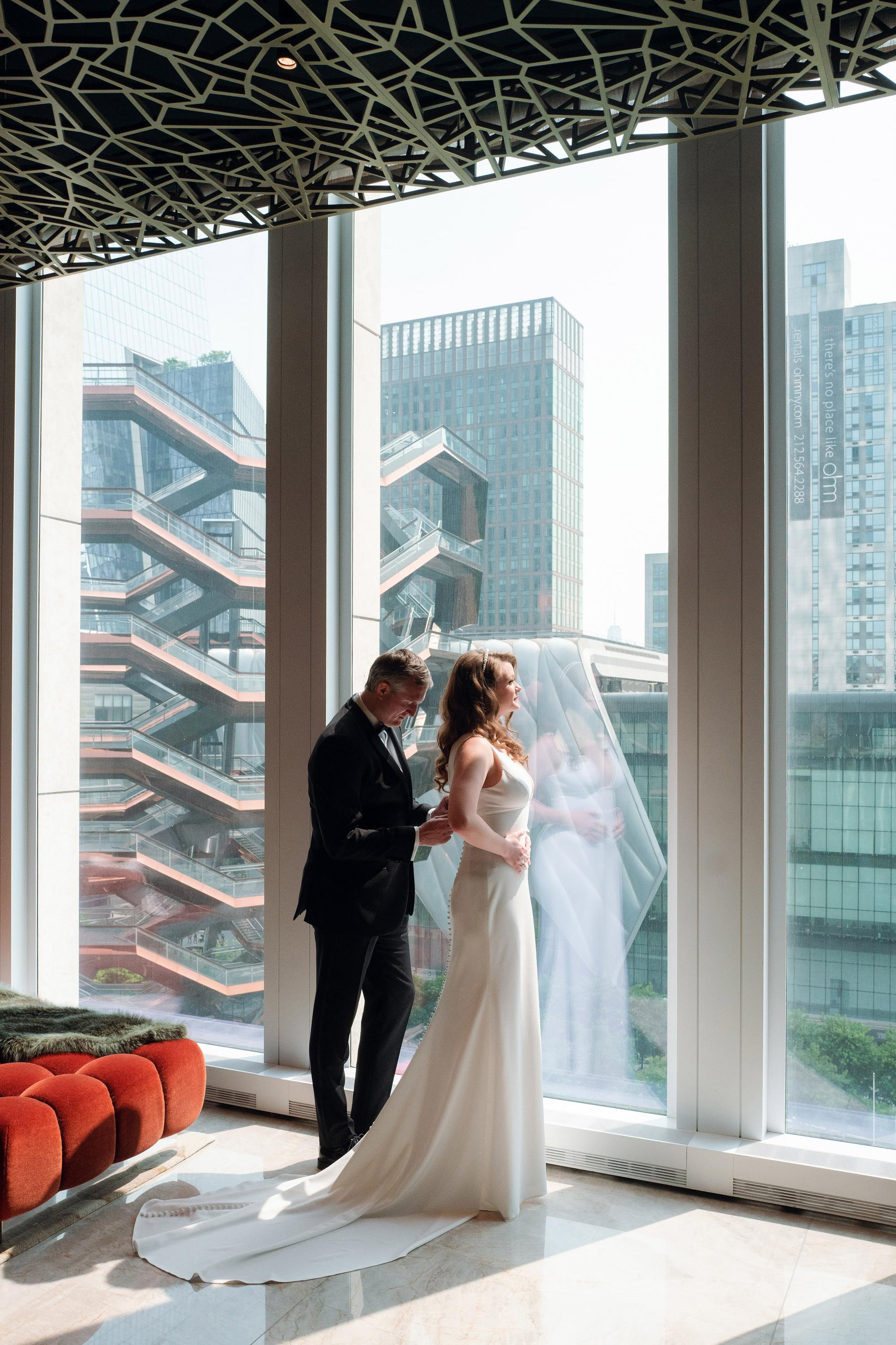 a bride and groom standing in front of a large window