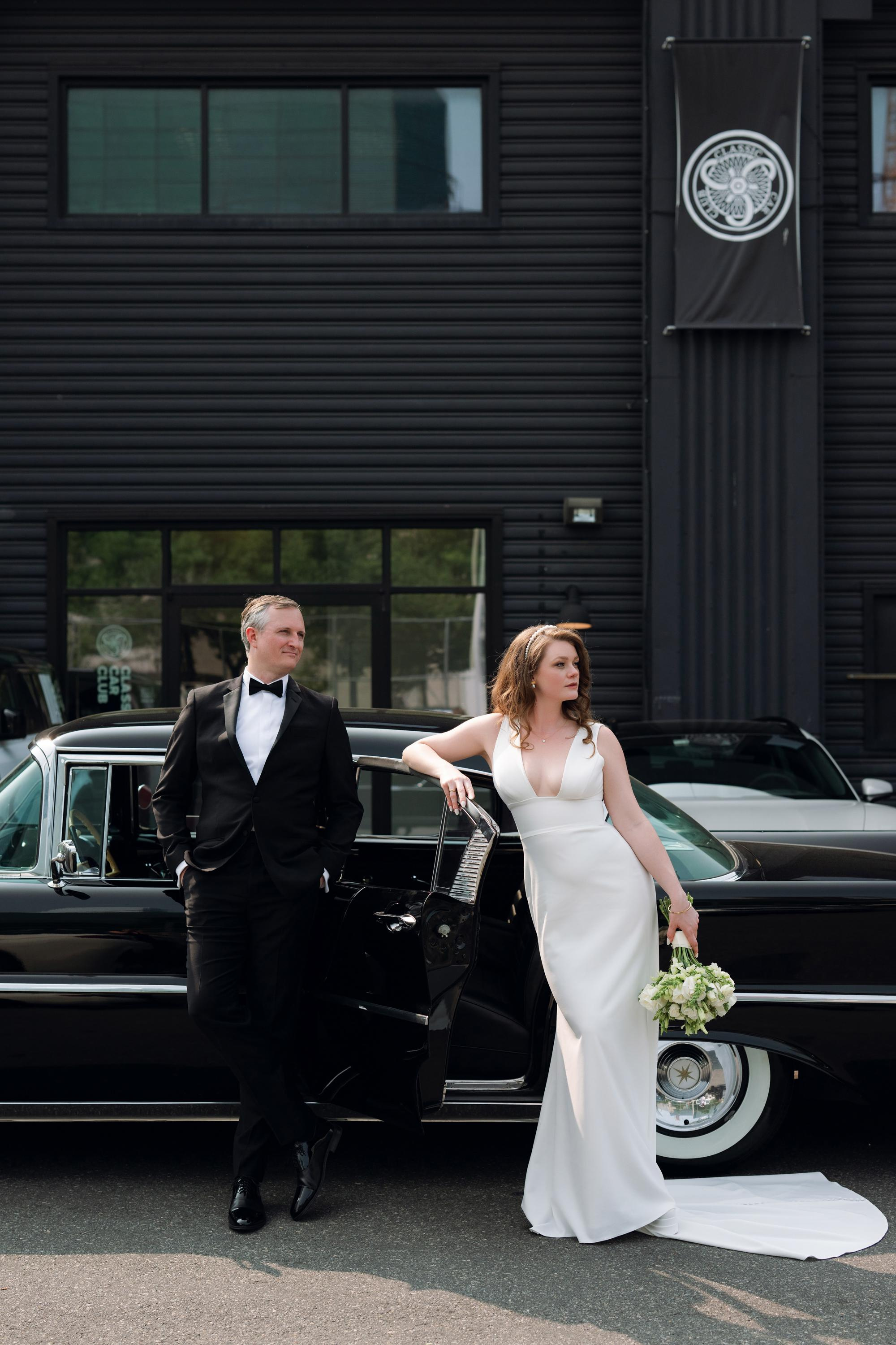 a bride and groom standing next to a classic car