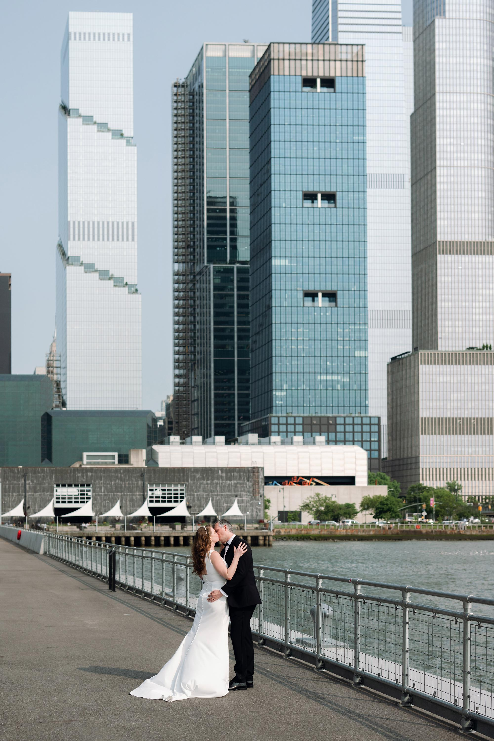 a bride and groom pose for a photo on the waterfront