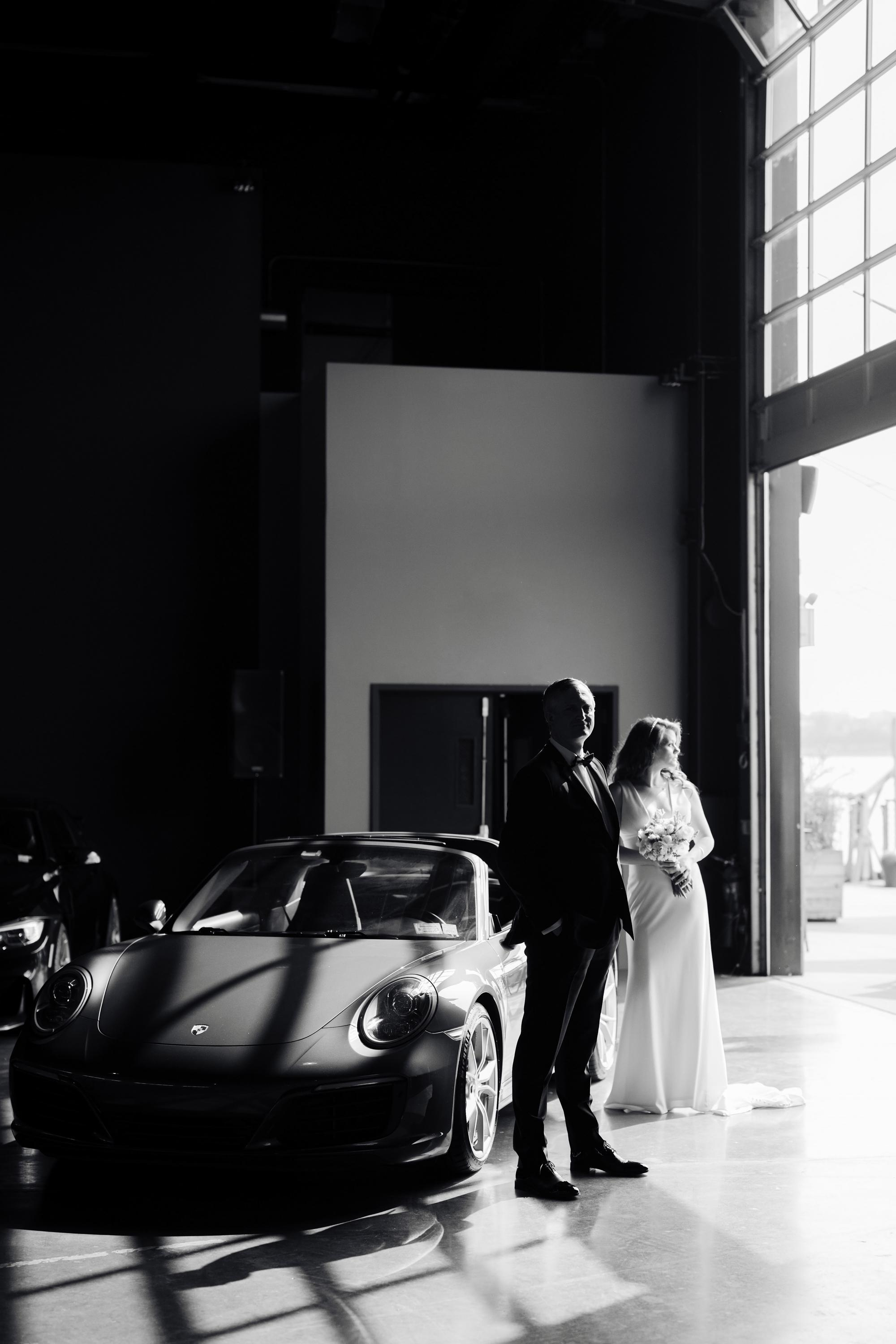 a bride and groom standing in front of a car