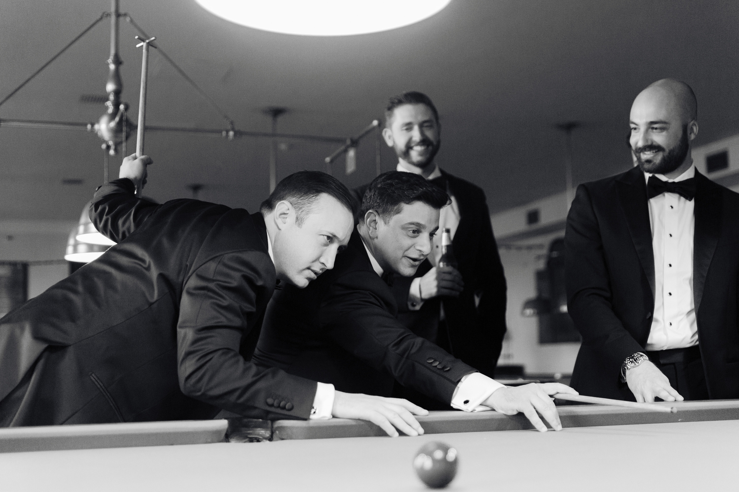 a group of men in tuxed suits playing pool