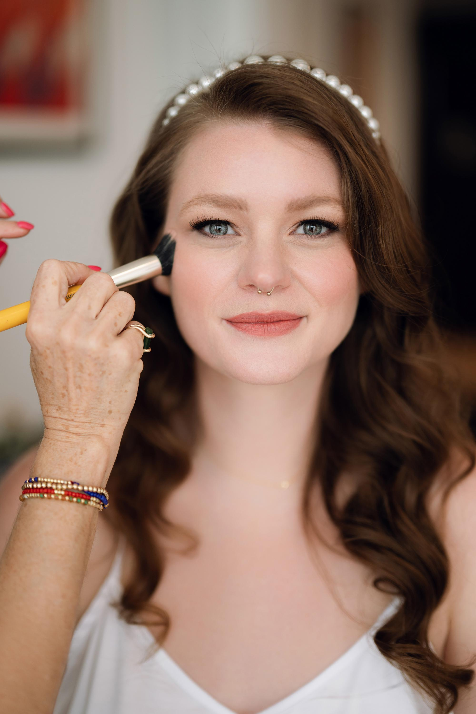 a woman is putting makeup on her face