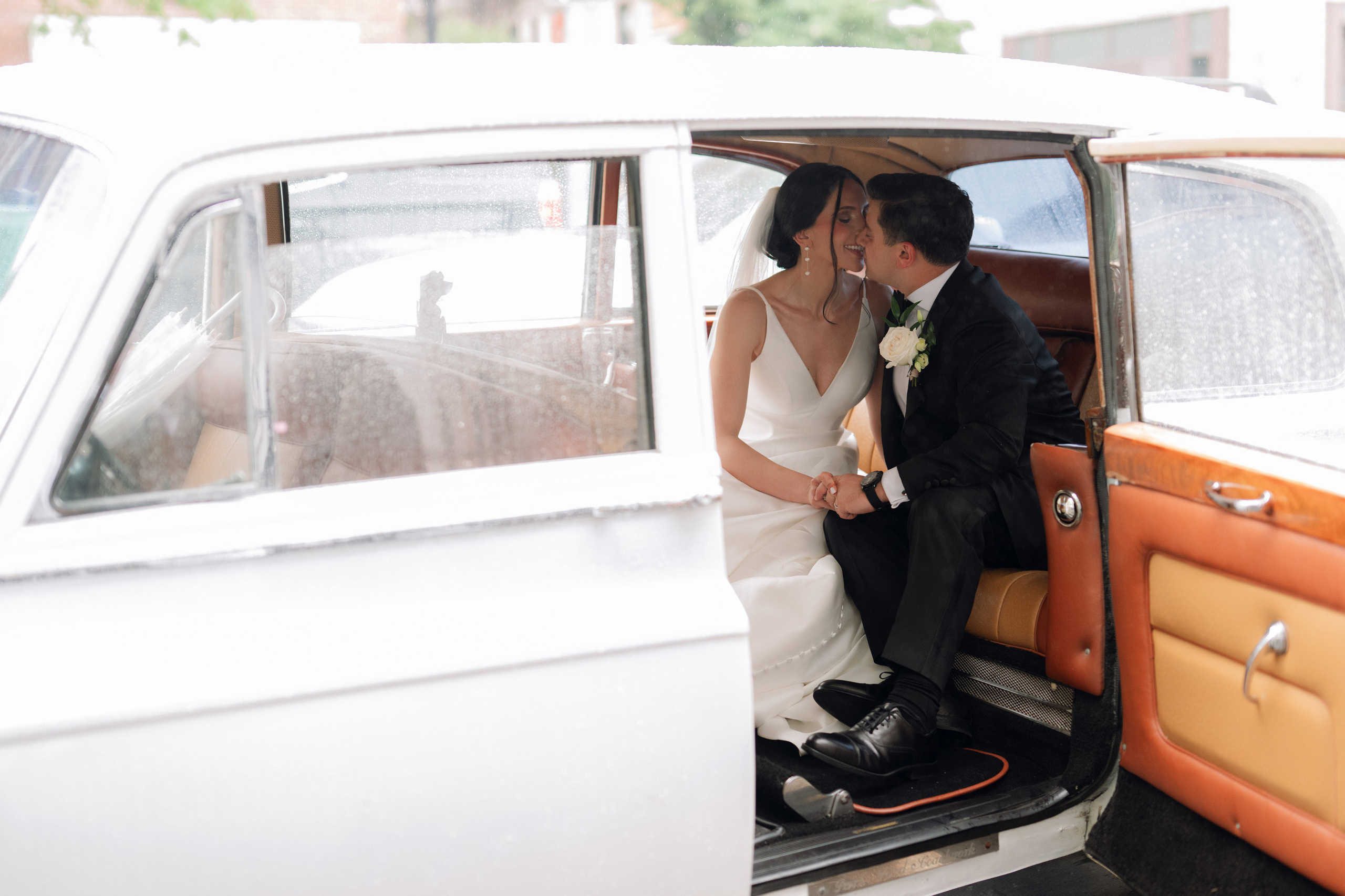 a bride and groom sitting in a vintage car