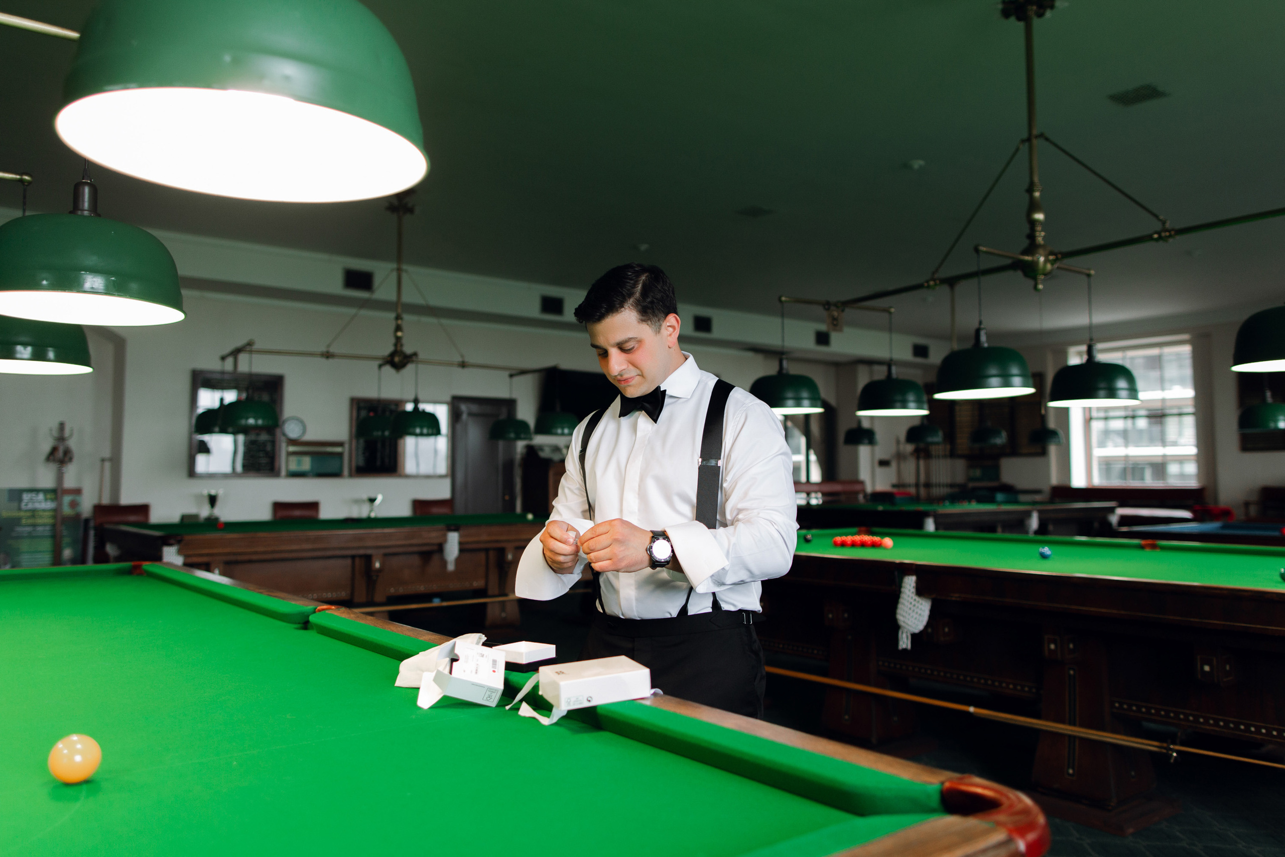 a man in a white shirt and black tie playing pool
