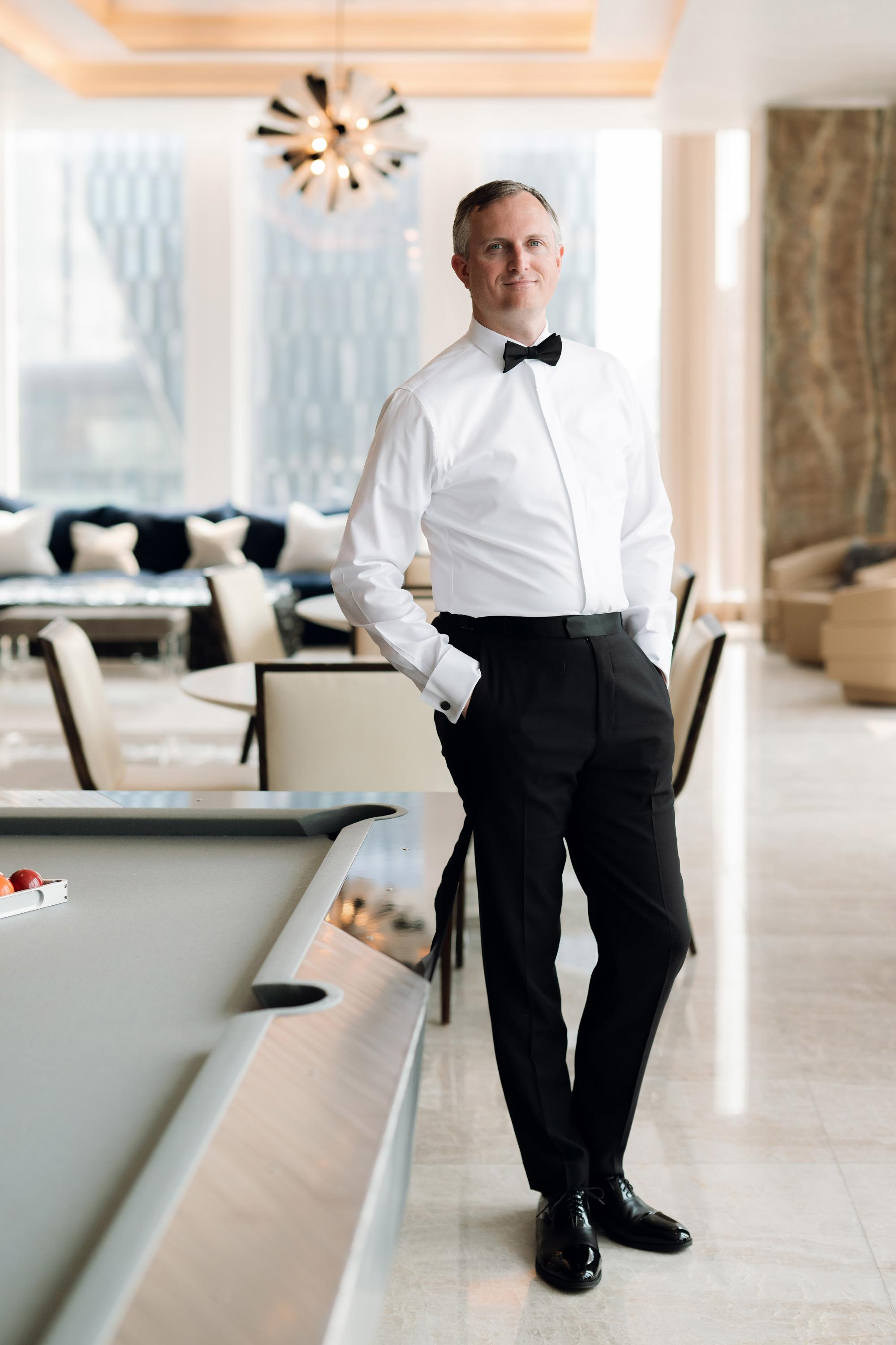 a man in a white shirt and black pants standing next to a pool