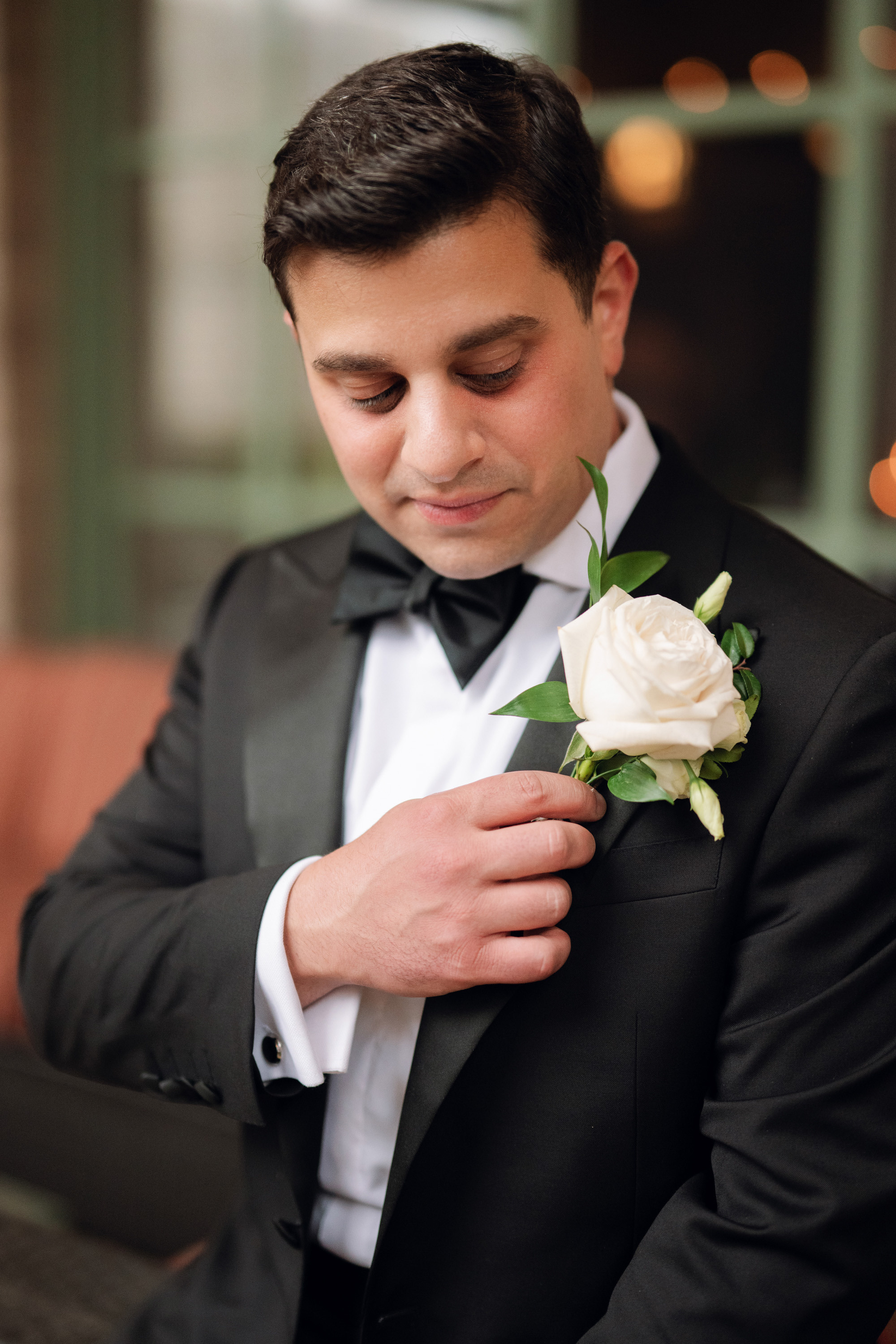 a man in a tuxed suit adjusting a flower