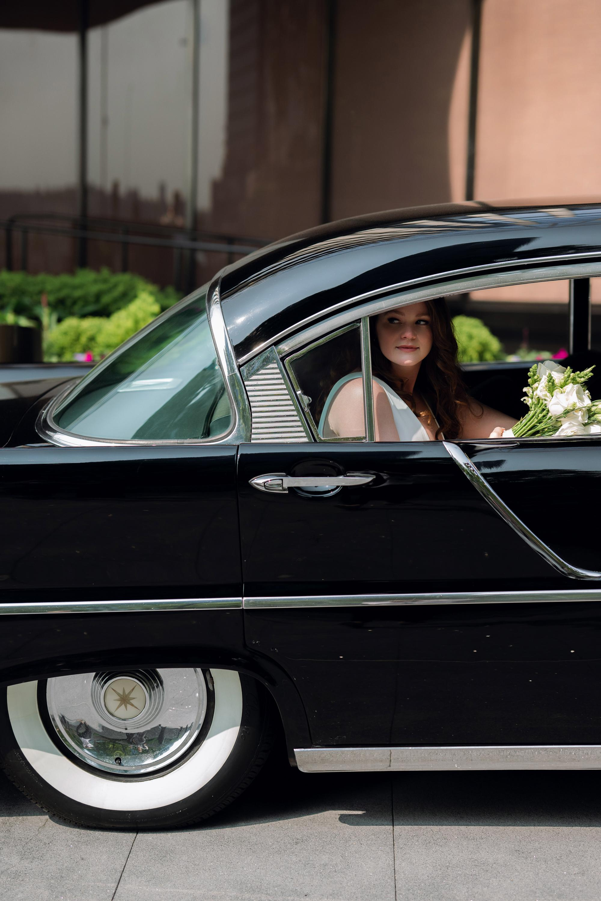 a woman in a black car with a bouquet in her hand