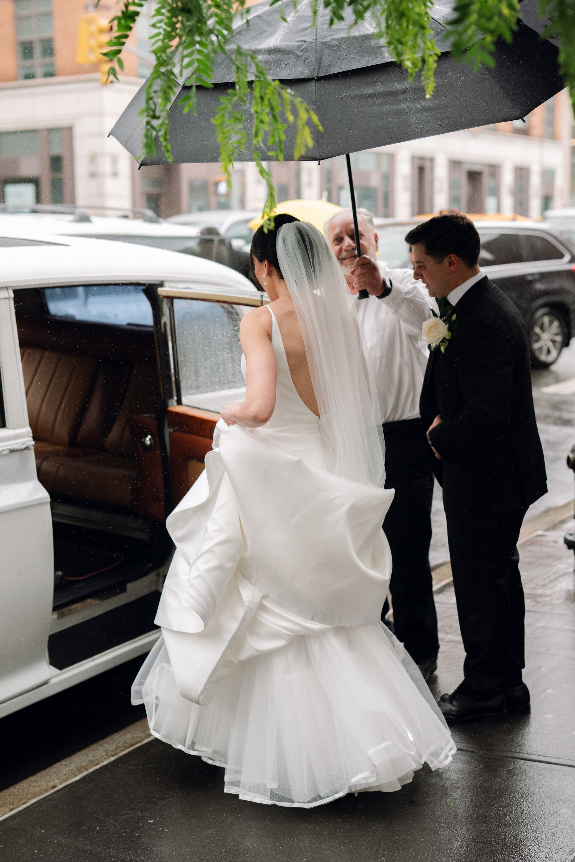 a bride and groom are standing in the rain