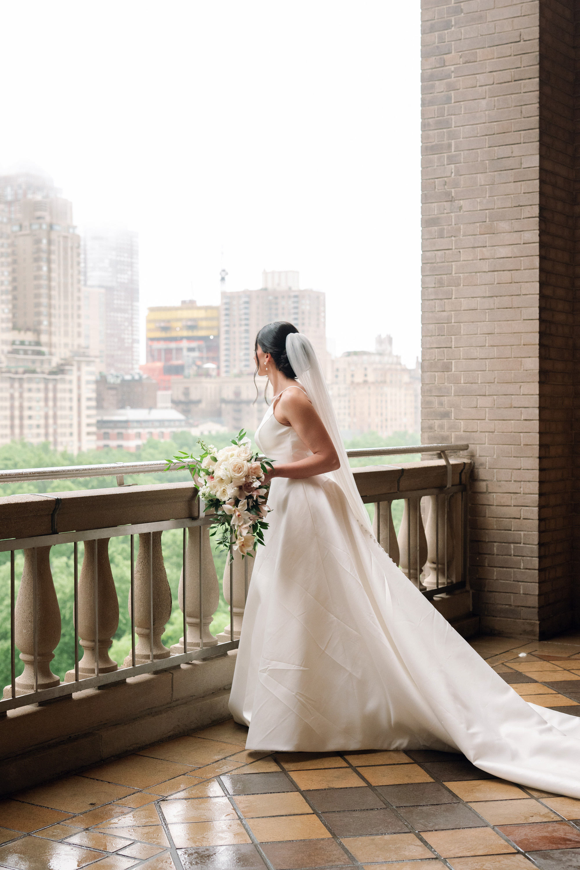 a bride sitting on a balcony looking out at the city