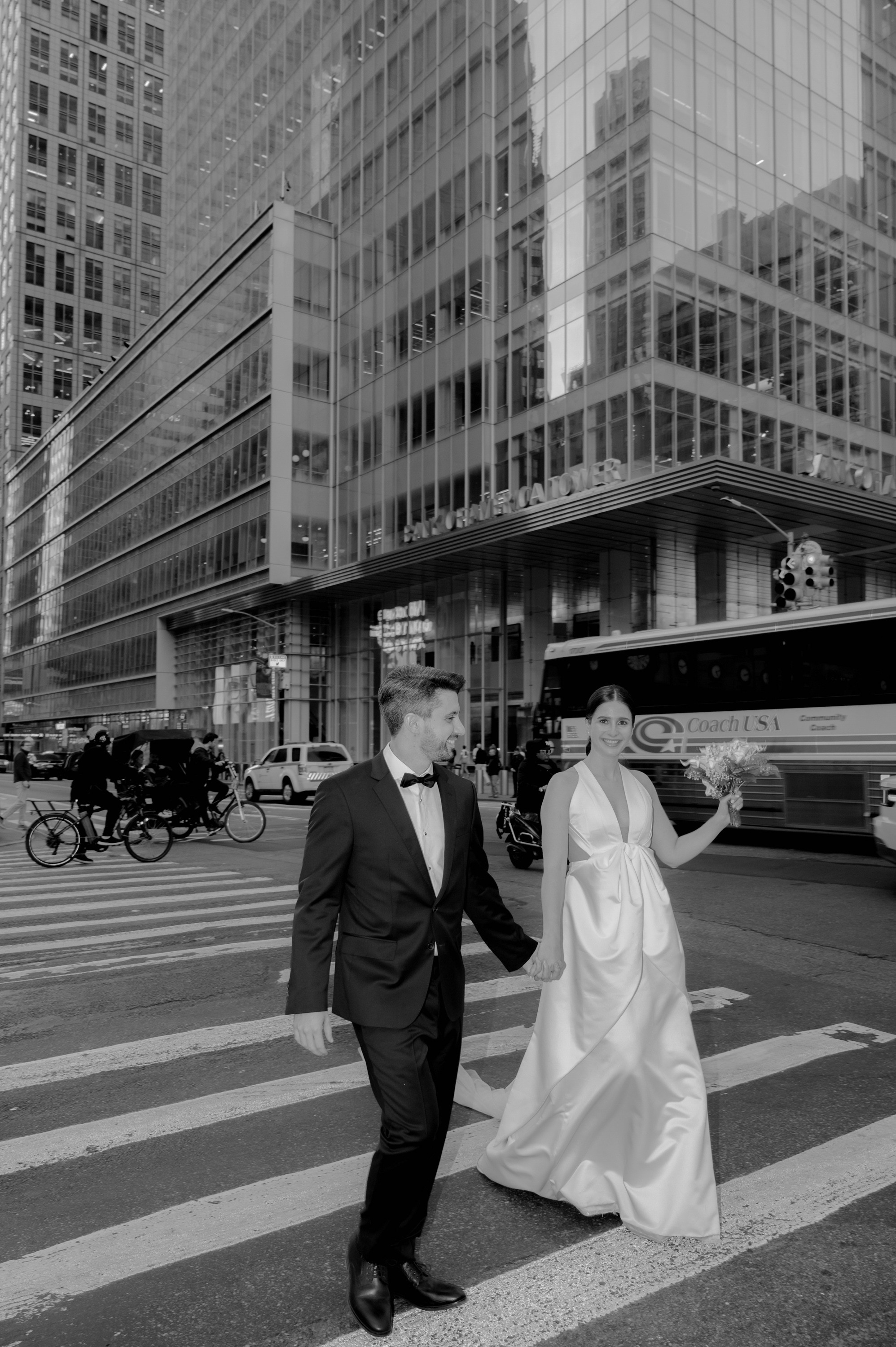 a bride and groom crossing the street in front of a building