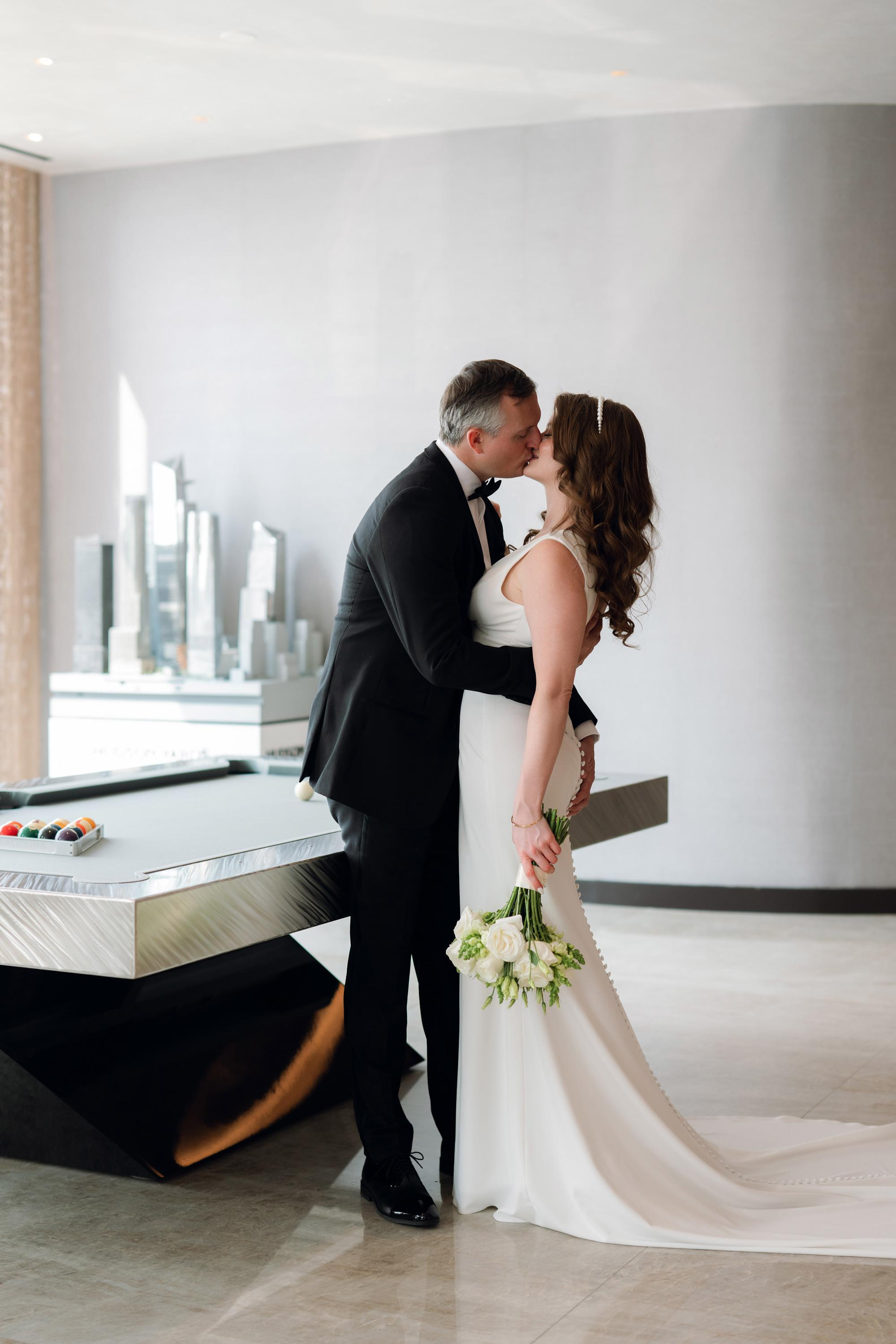a bride and groom kissing in a modern room