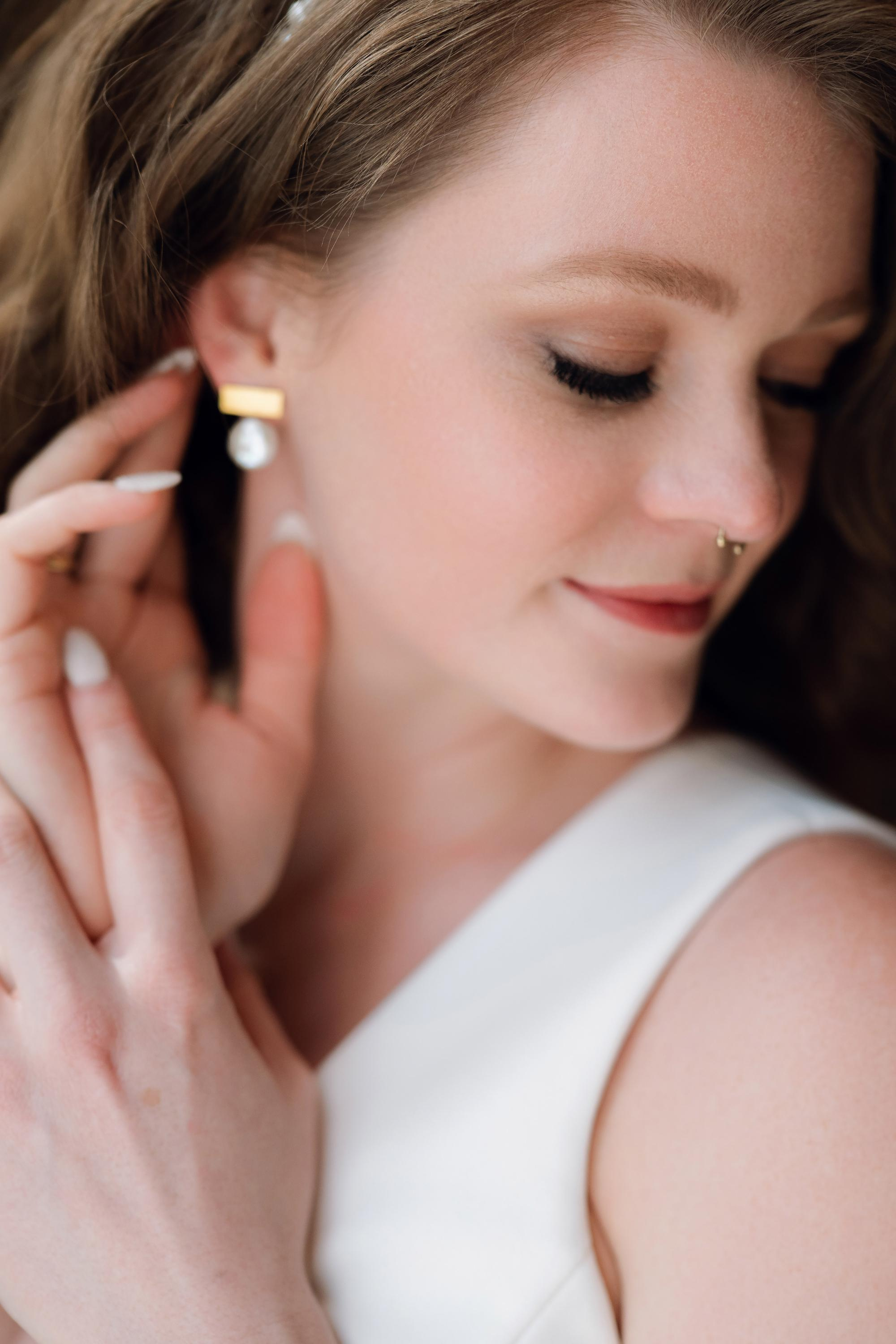 a woman in a white dress is putting her earrings