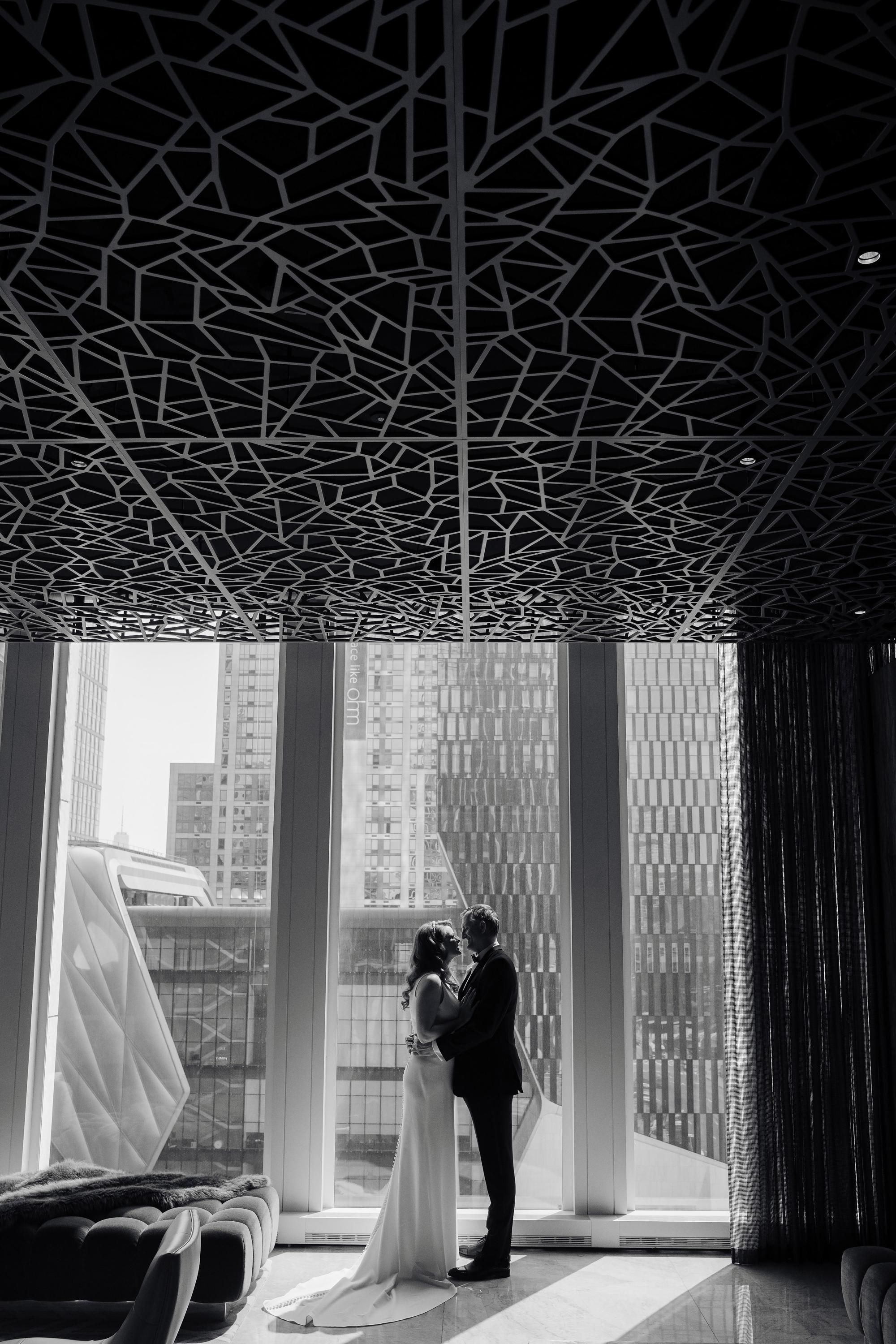 a bride and groom standing in front of a window
