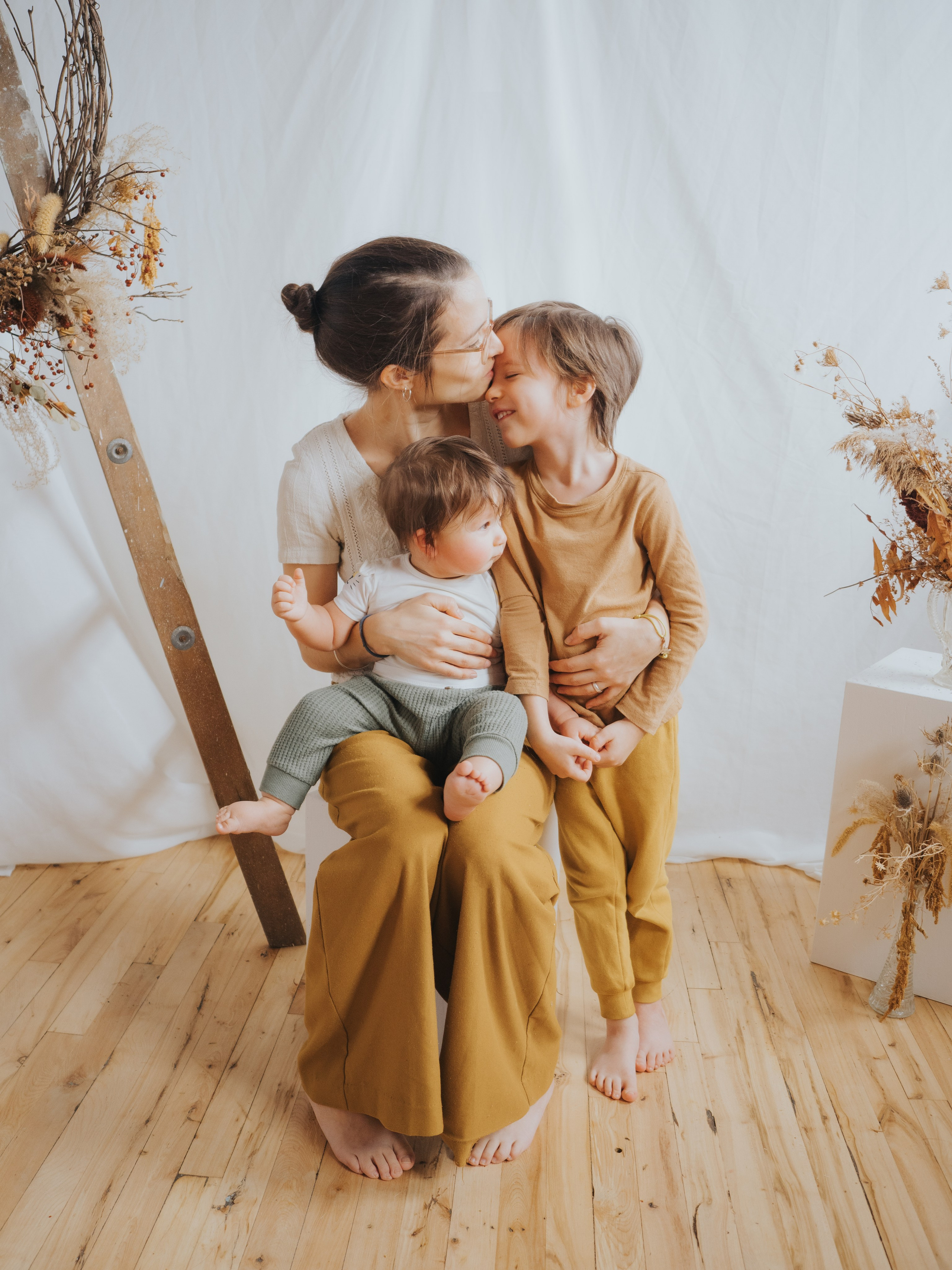 Mother giving older sibling a kiss on the forehead.