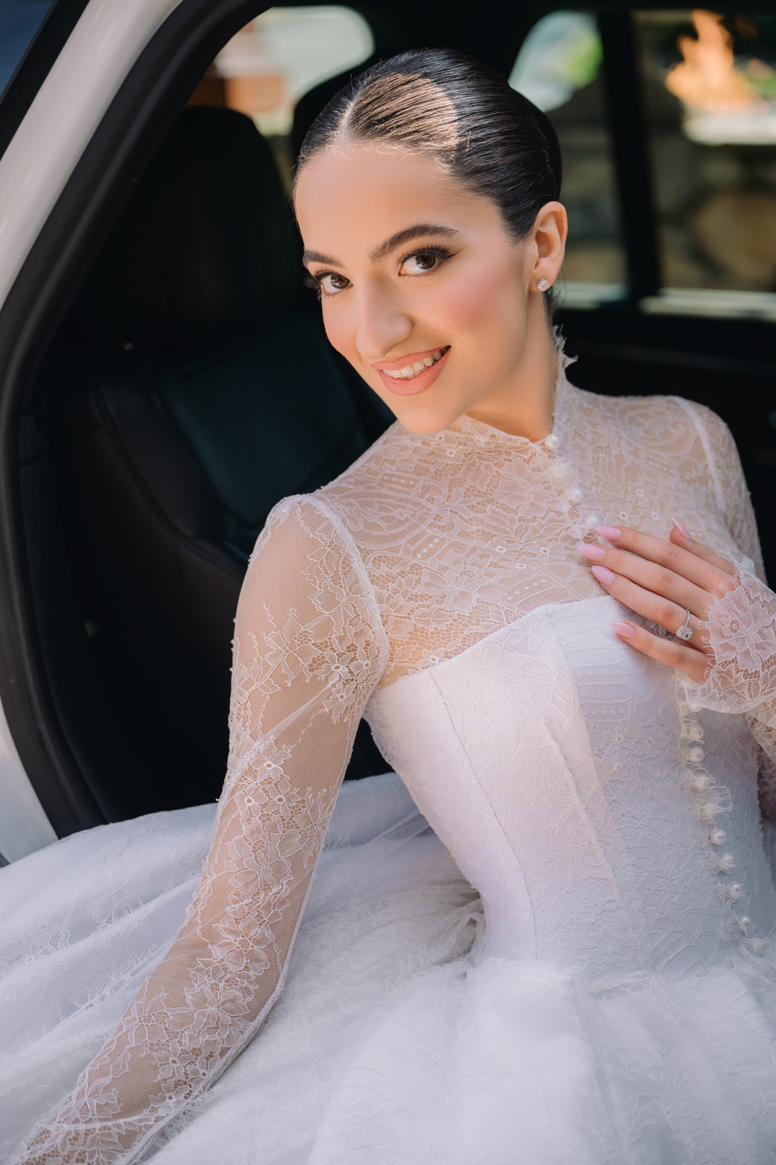 a woman in a white dress is sitting in the back of a car
