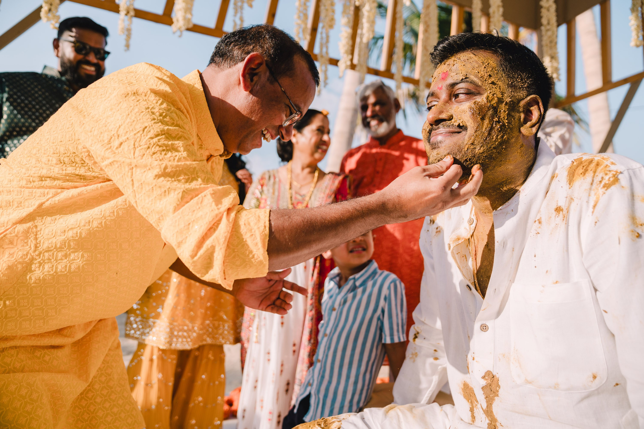 Indian gentleman is touching the groom with turmeric on a traditional ceremony