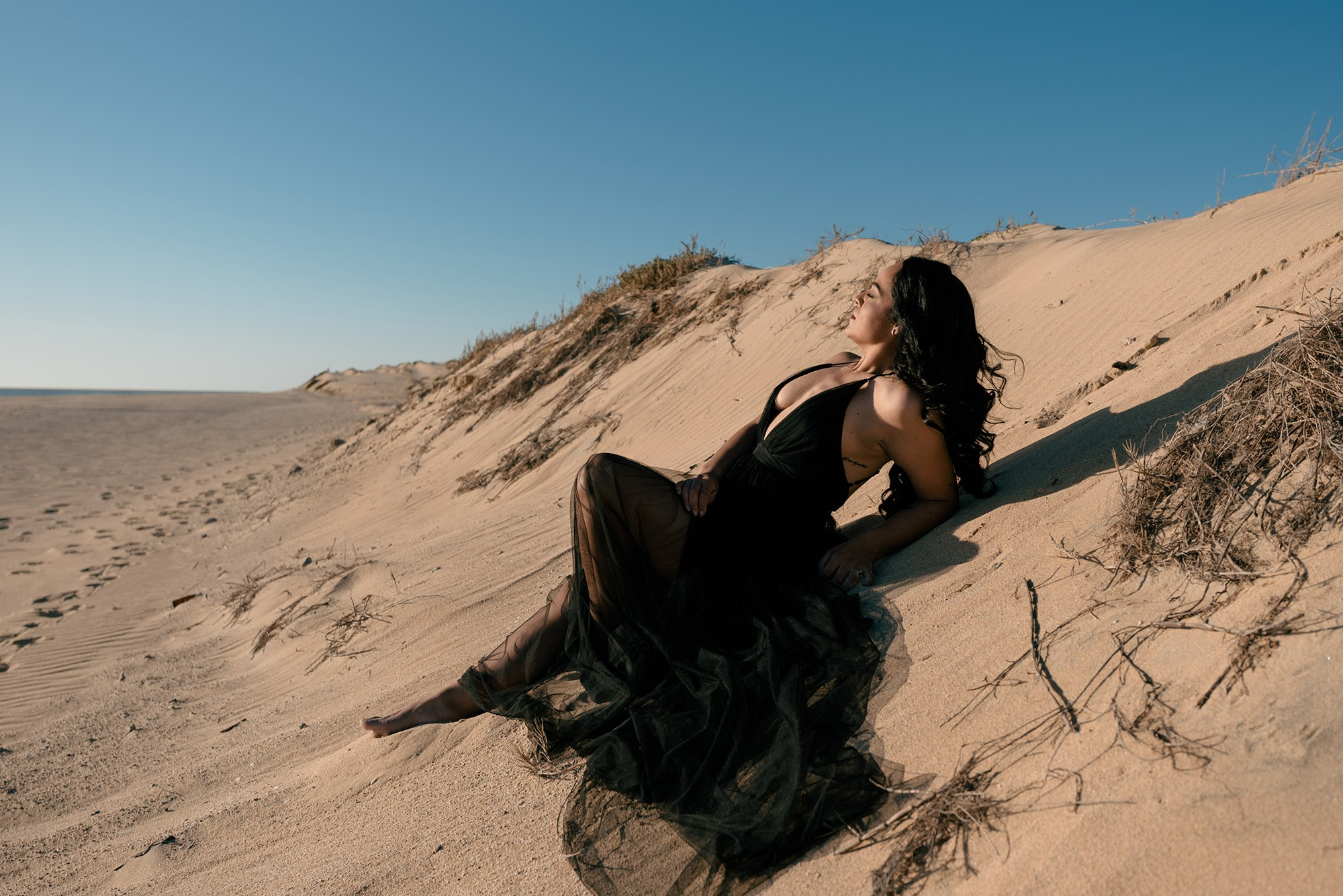 Editorial lifestyle portrait of woman in black dress on sand dunes near Cabo San Lucas, Baja California Sur