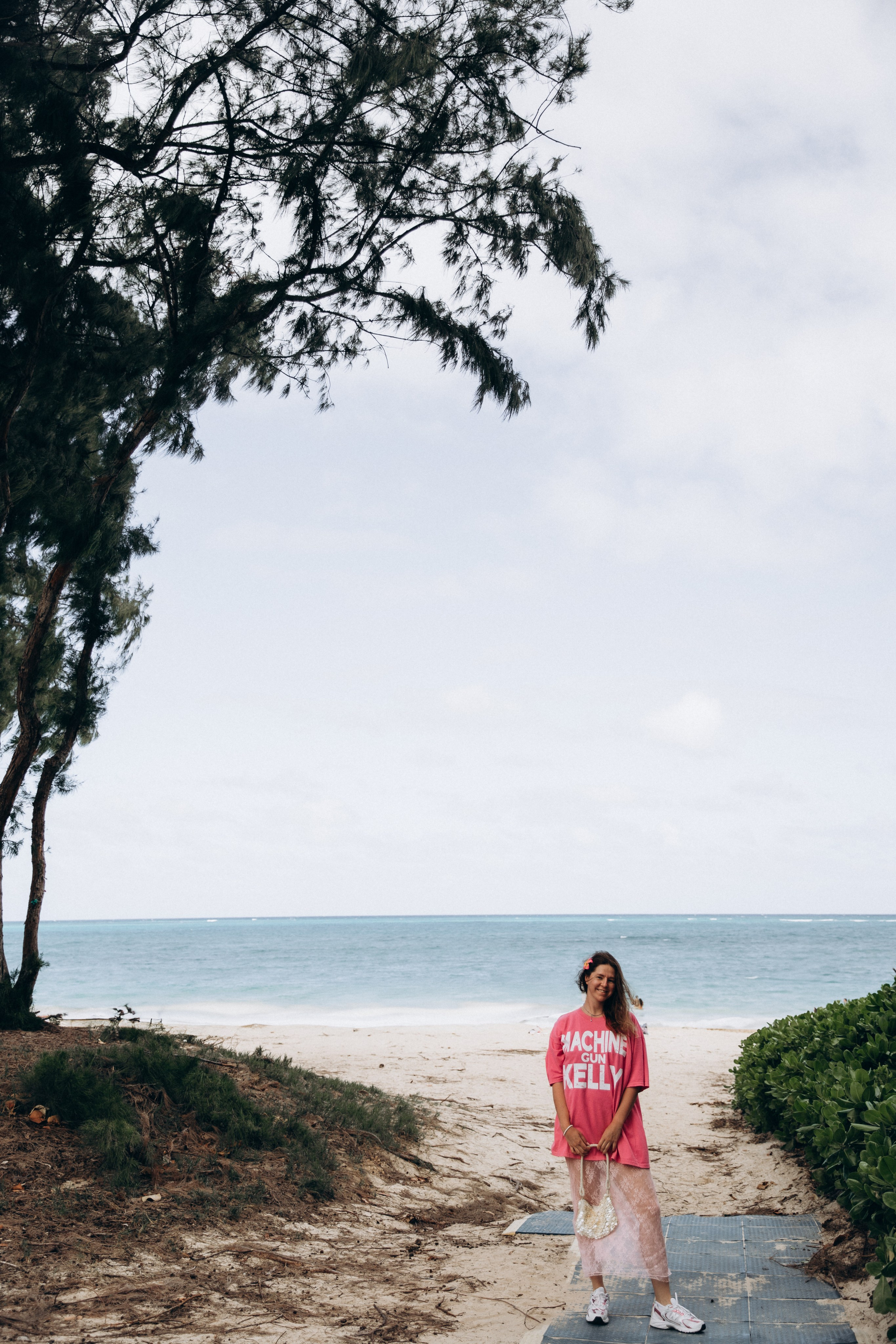 Beach outfit with pink t-shirt, lace skirt, and seashell handbag at Waimanalo Beach