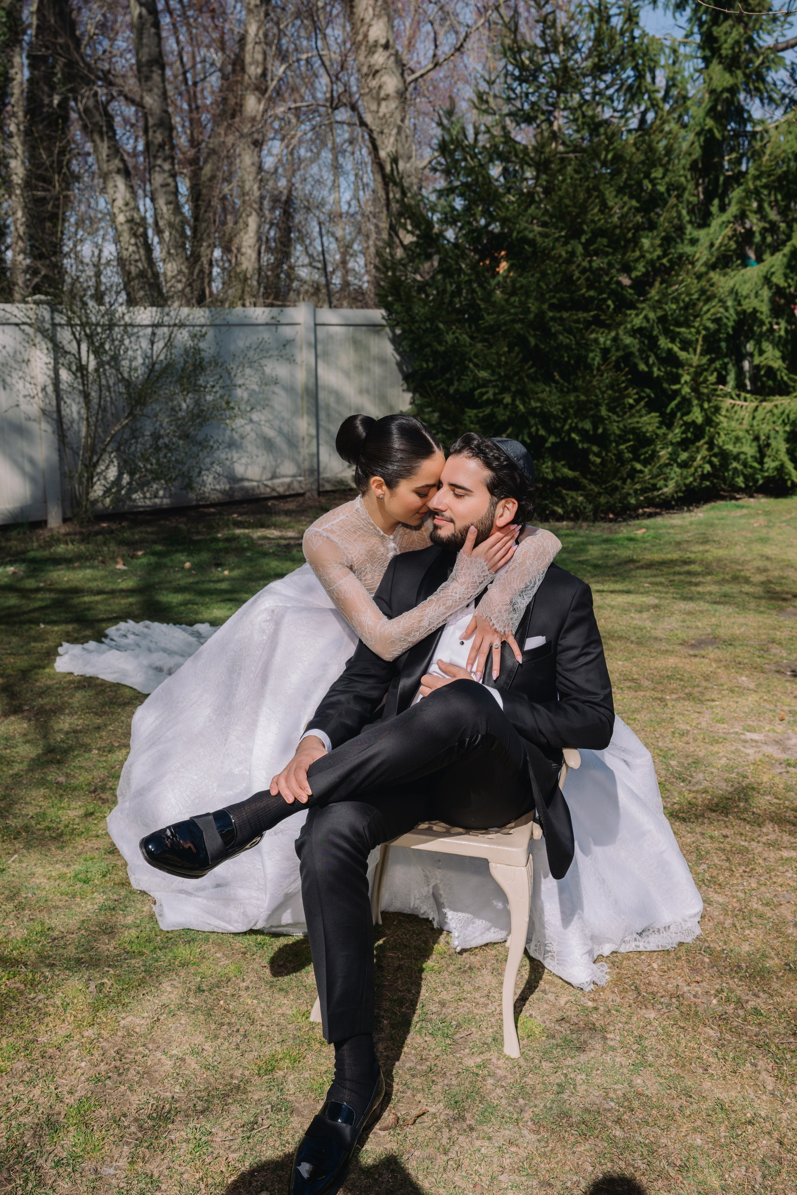 a bride and groom sitting on a bench in the grass
