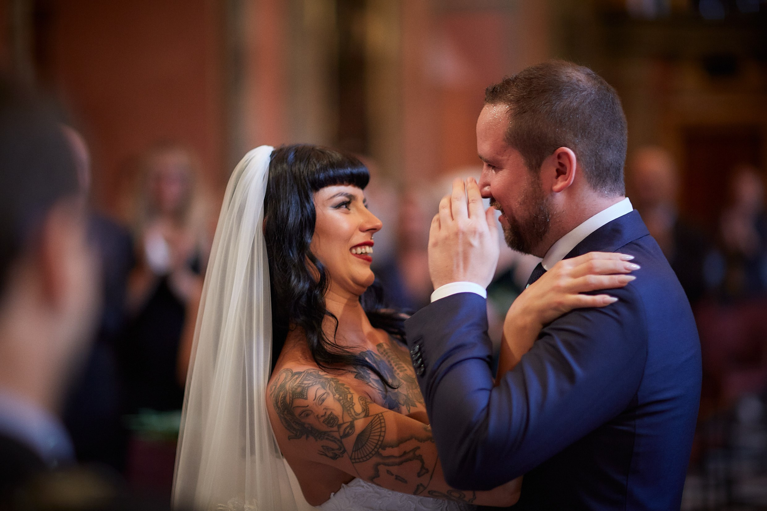 Emotional groom wiping tear while bride watches lovingly.