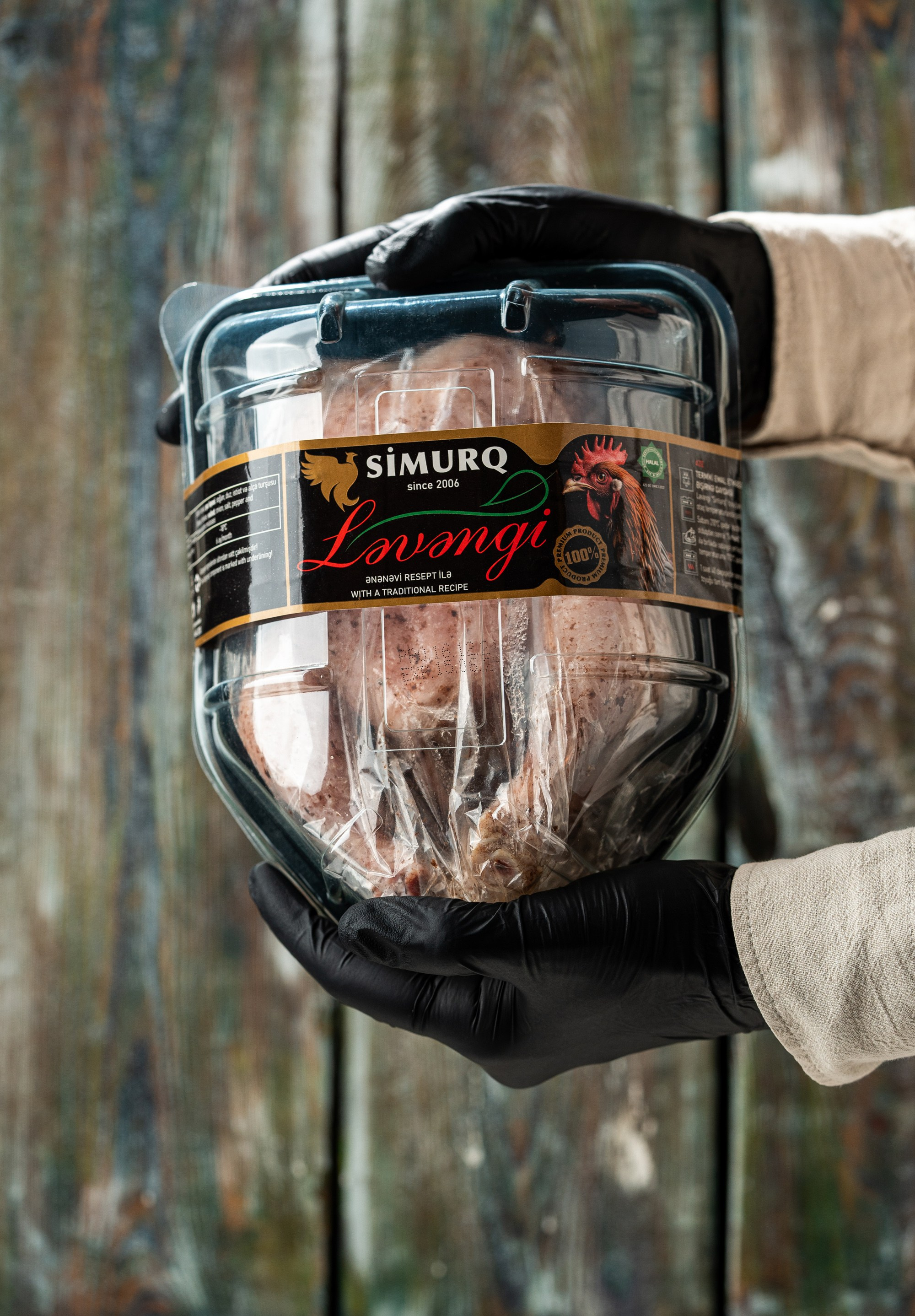 Simurq brendinə aid Ləvəngi məhsulunun əlində təqdimatı – rustik fonda toyuq məhsulu qablaşdırma fotoqrafiyası | halal məhsul vizualı