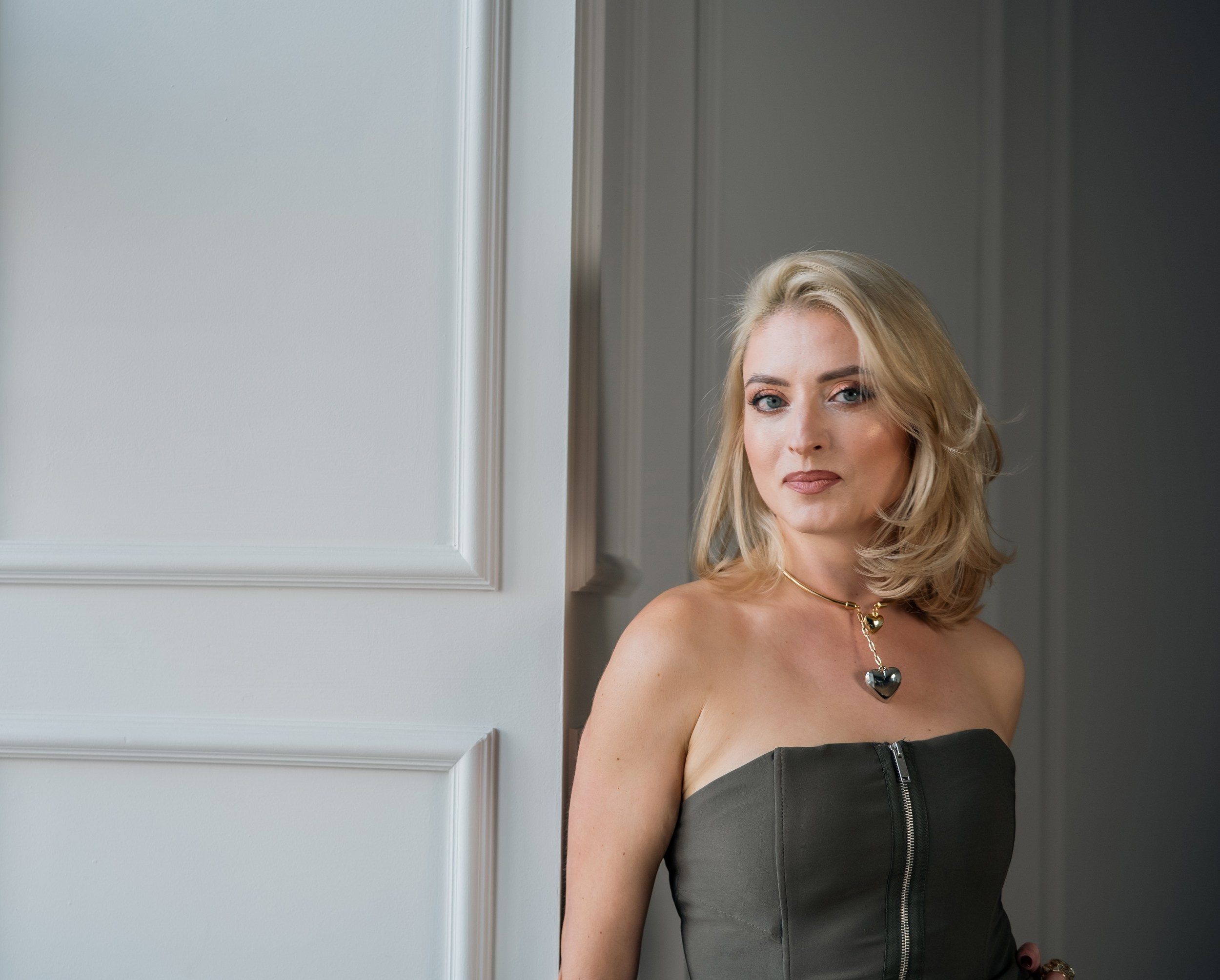 A woman in a beautiful dress stands against the wall in the studio, Riga photographer