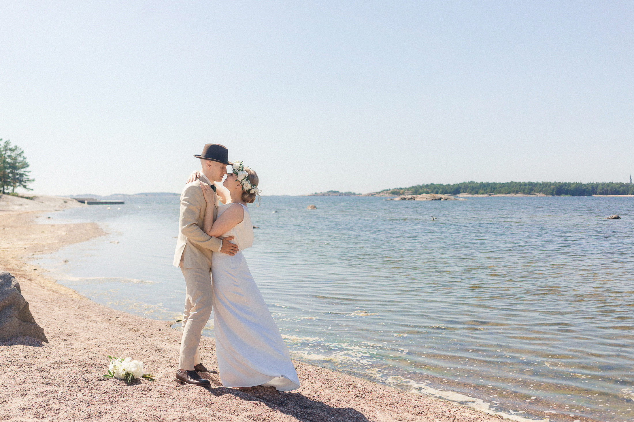 hääpotretti jossa hääpari suutelee Bellevue rannalla Hangossa