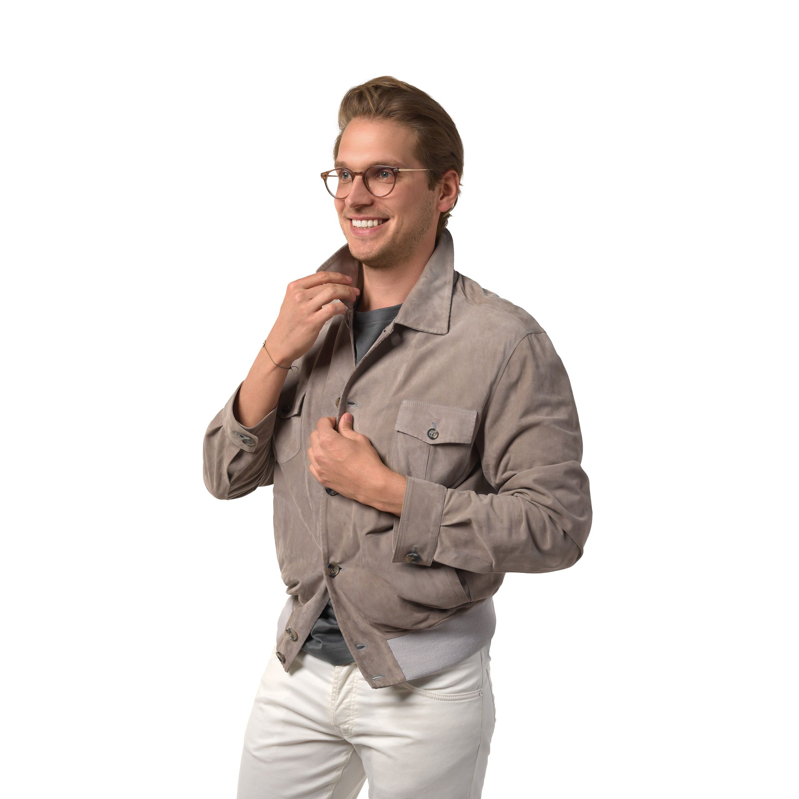 Model in beigefarbener Jacke, greift am Kragen, freundlicher Ausdruck, Studioaufnahme.