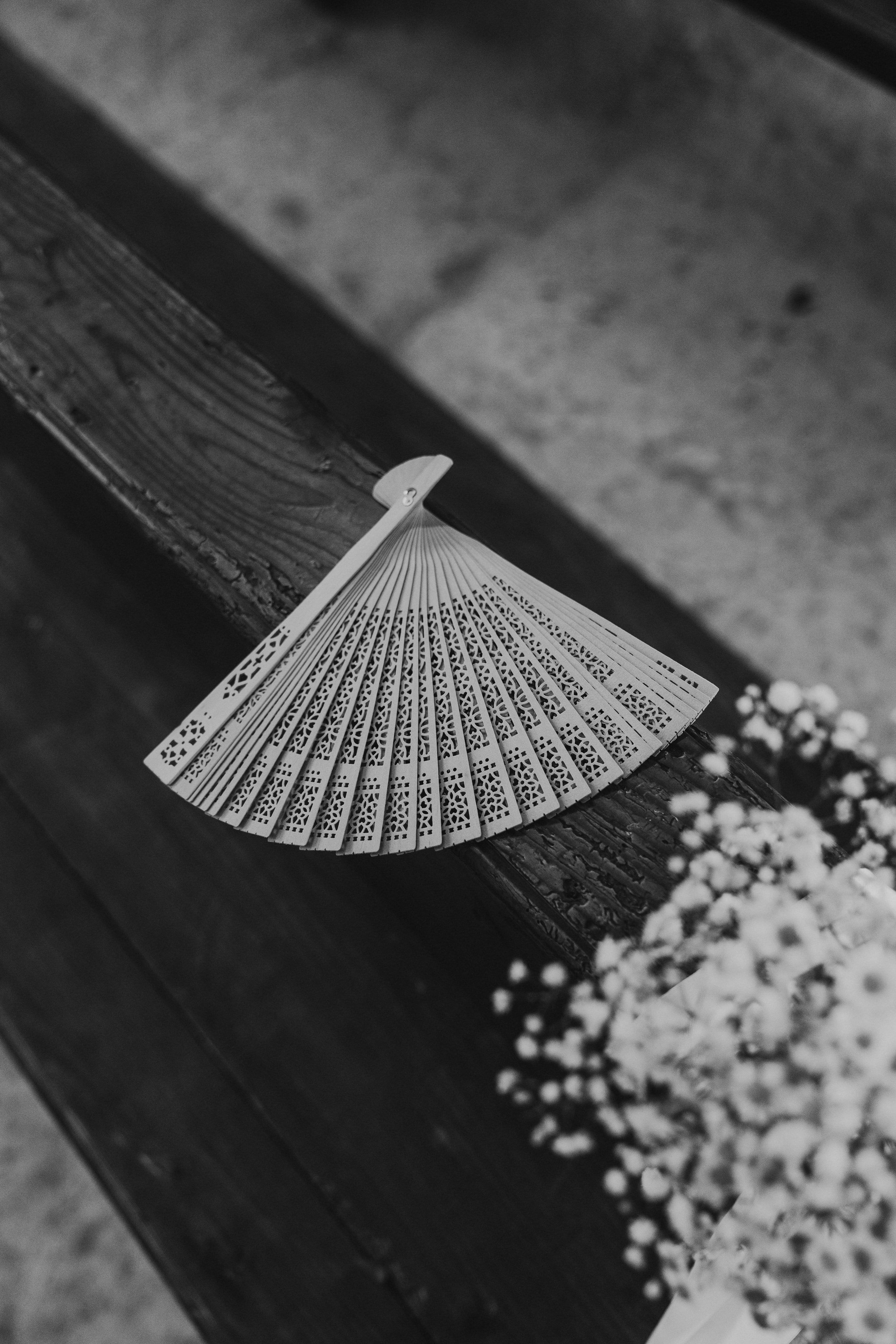 Flat lay de casamento minimalista com leque e pétalas brancas delicadas