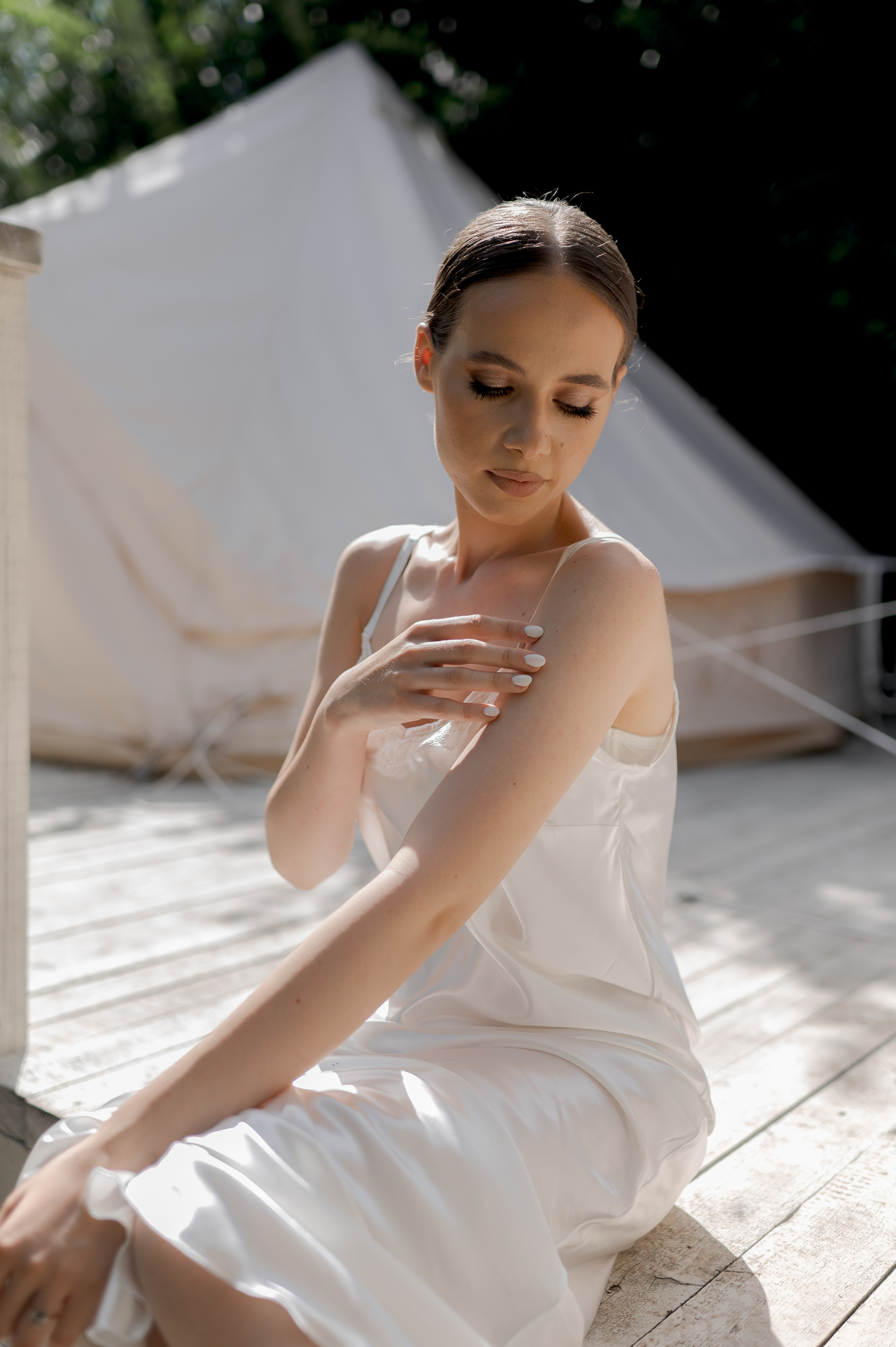 In the tranquil ambiance of the wedding morning, the delicate bride embraces the beauty of her satin dress, its soft fabric reflecting her refined taste and timeless style.