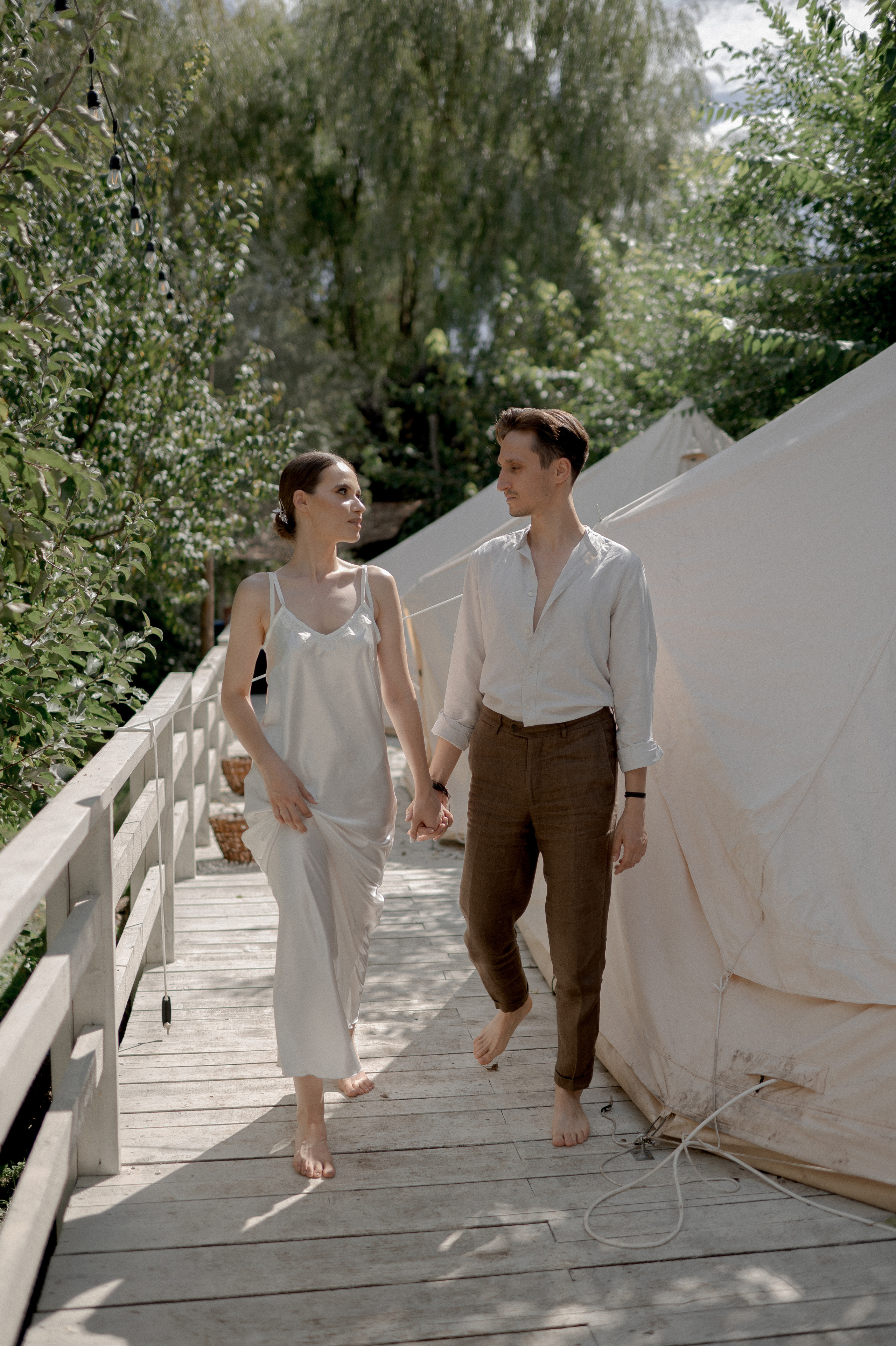 Within a serene garden setting, glamping tents become a haven for the couple's wedding morning, offering seclusion and intimacy as they share loving and tender moments.