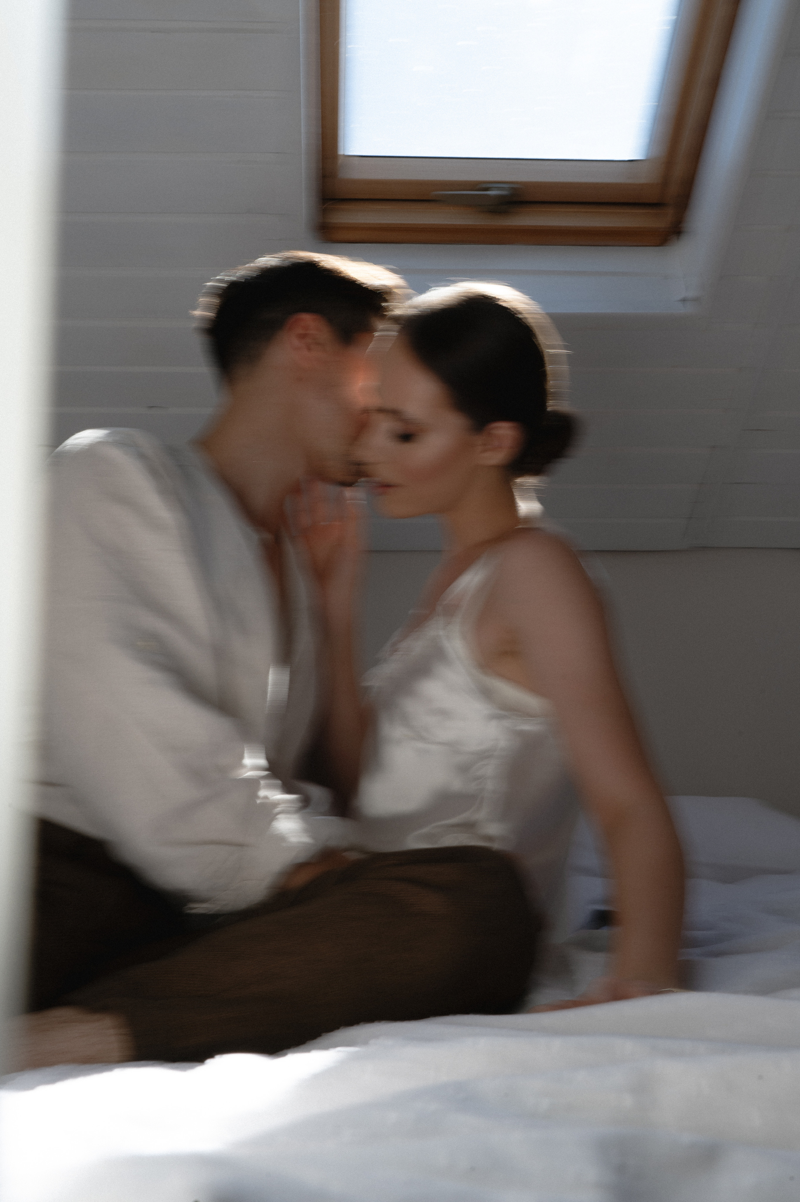 Intimate wedding morning captured with a slow shutter speed by the photographer, as the couple enjoys cozy moments in bed together, sharing love and anticipation for their special day - a romantic start to their journey as a newly married couple.