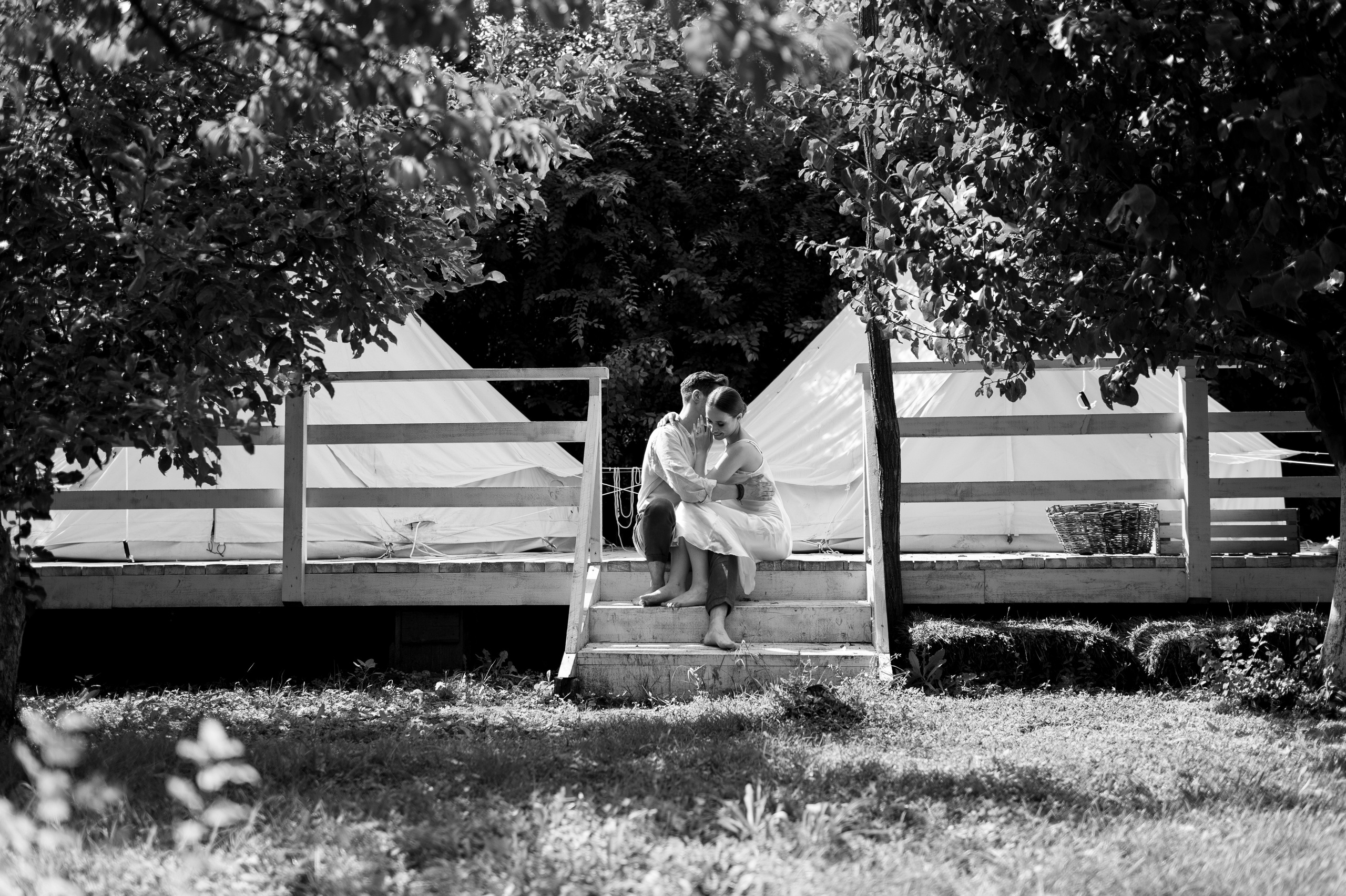 Amidst the tranquility of a secluded garden, the couple's wedding morning unfolds in the embrace of glamping tents, offering an intimate sanctuary for their cherished moments of love and tenderness.