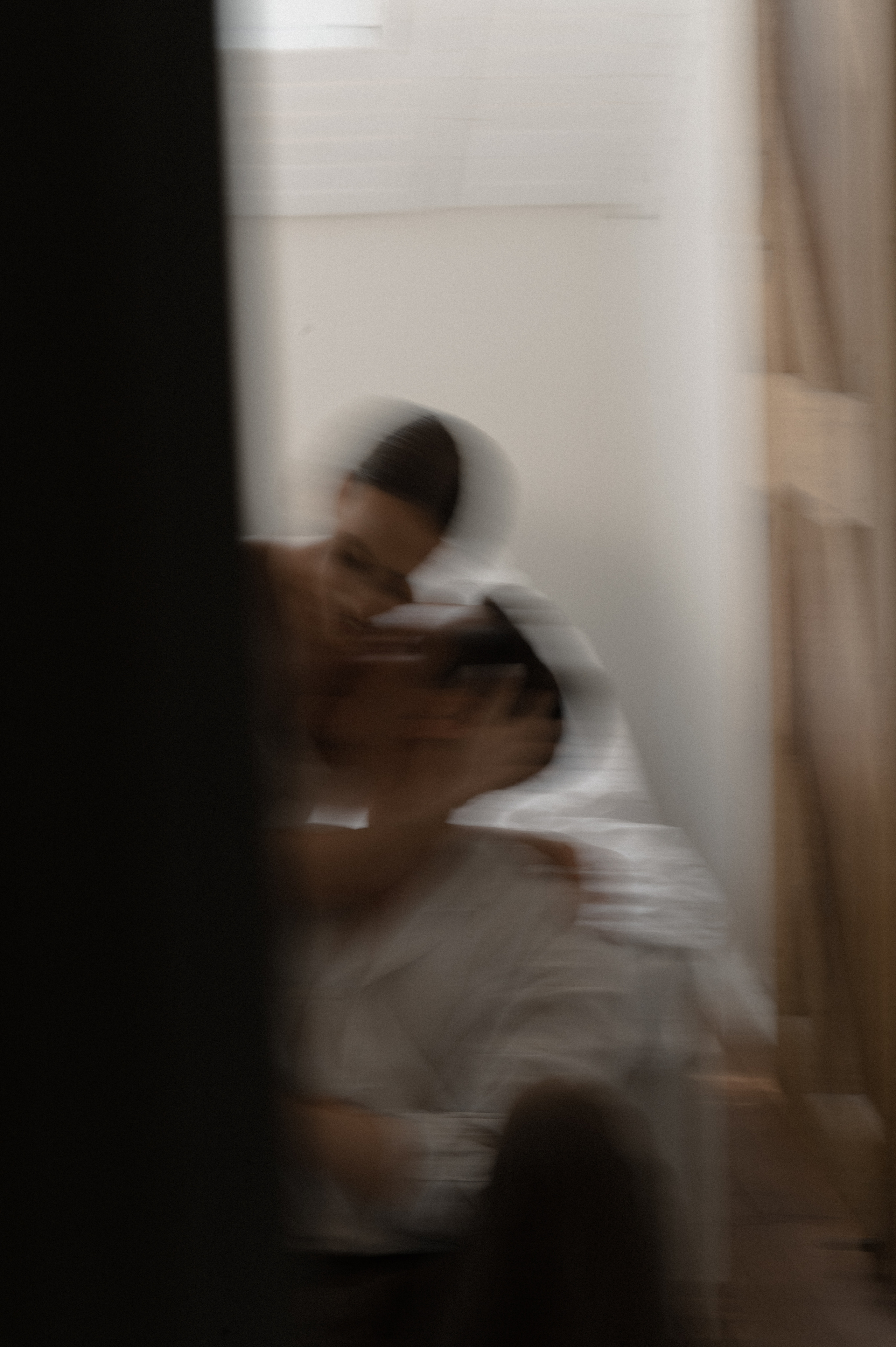 Utilizing a slow shutter speed, the photographer captures the couple tenderly kissing in the room, the image infused with a sense of intimacy and passion.