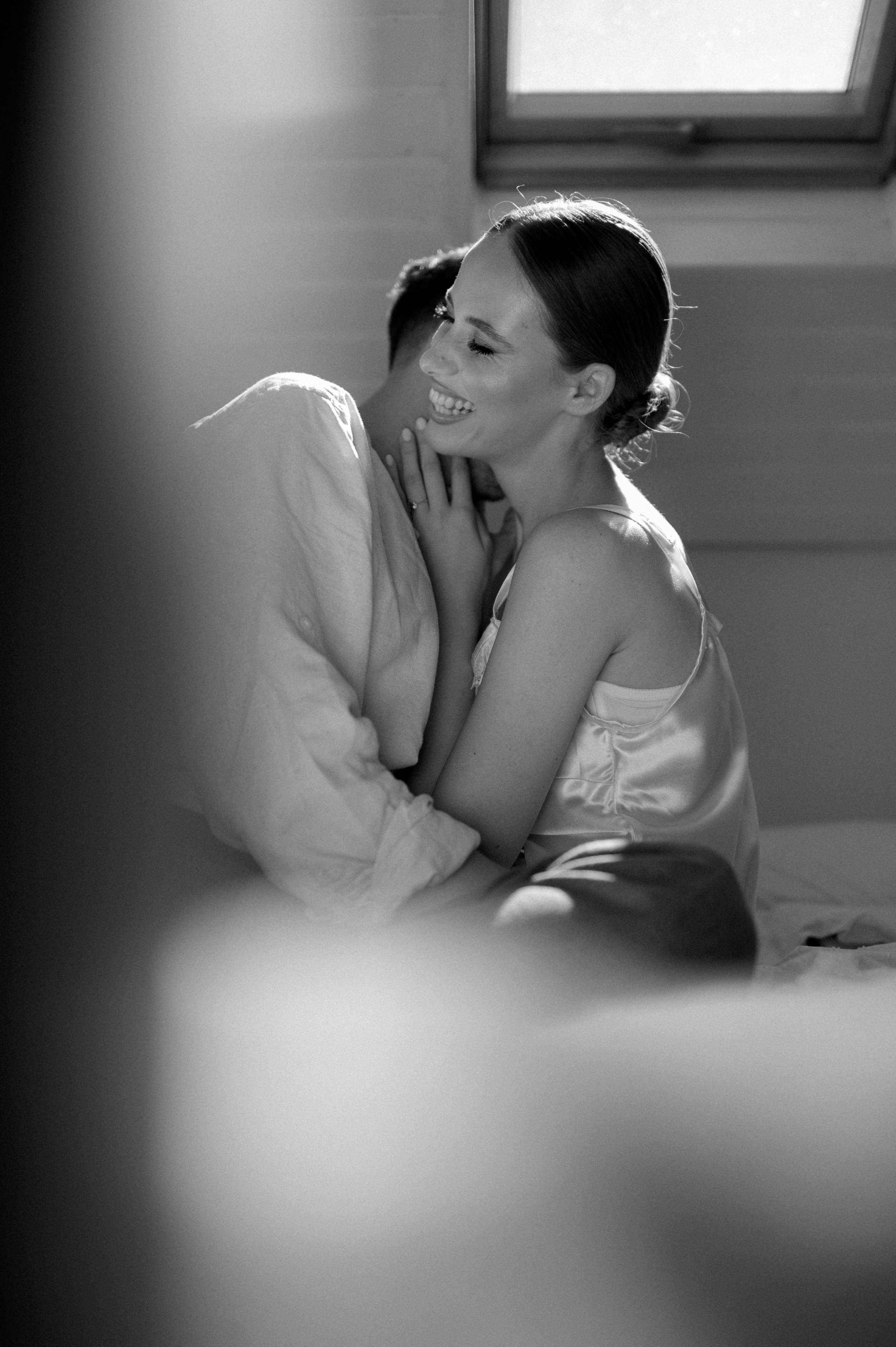 Intimate wedding morning beautifully captured in black and white by the photographer, as the couple enjoys cozy moments in bed together, radiating love and anticipation for their special day - a timeless start to their journey as a newly married couple.