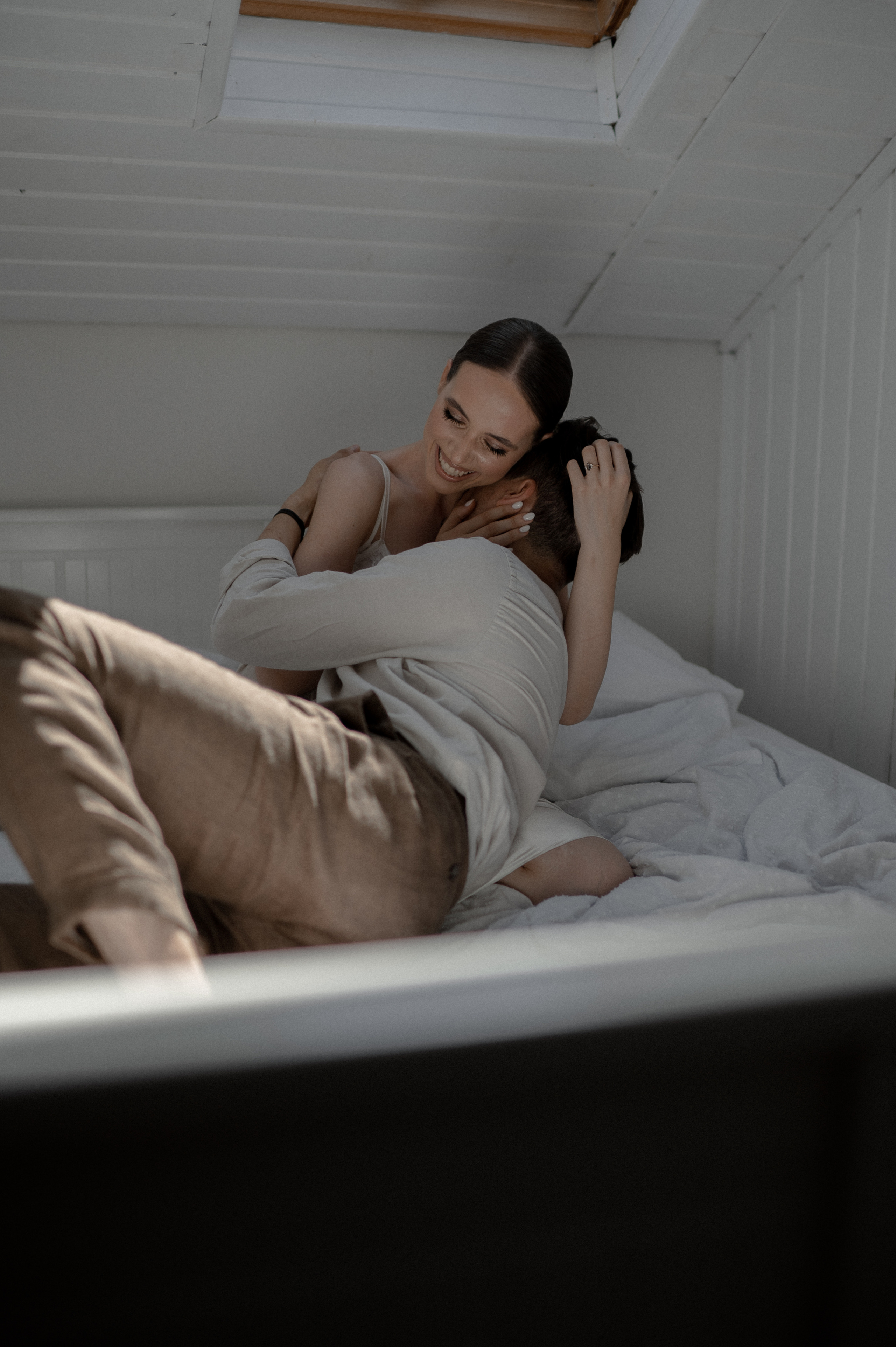 A loving embrace in bed marks the beginning of the couple's wedding day, radiating warmth, affection, and anticipation.