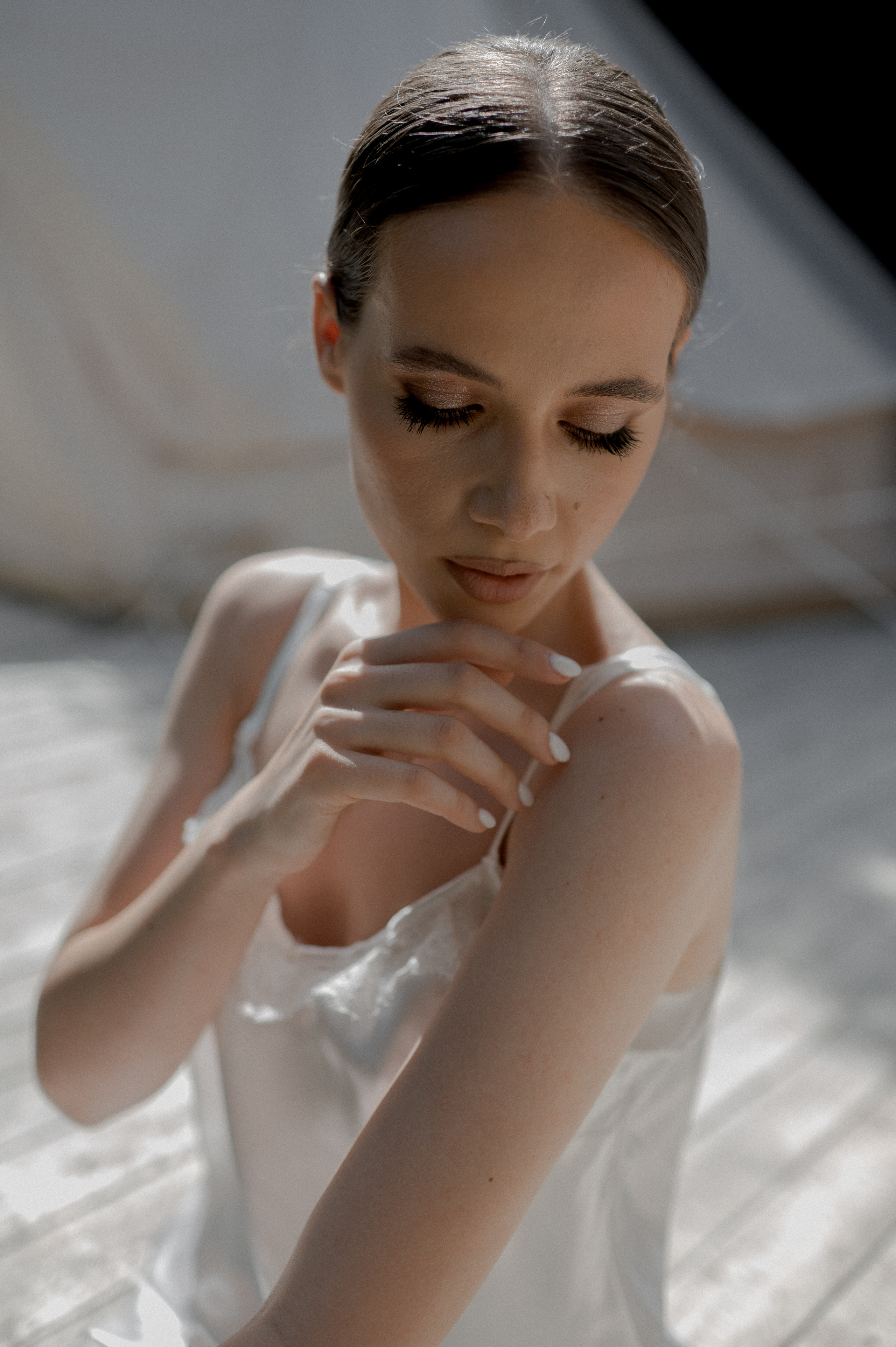 Bathed in soft morning light, the delicate bride exudes a timeless allure in her satin dress, capturing the essence of romance on her wedding day.