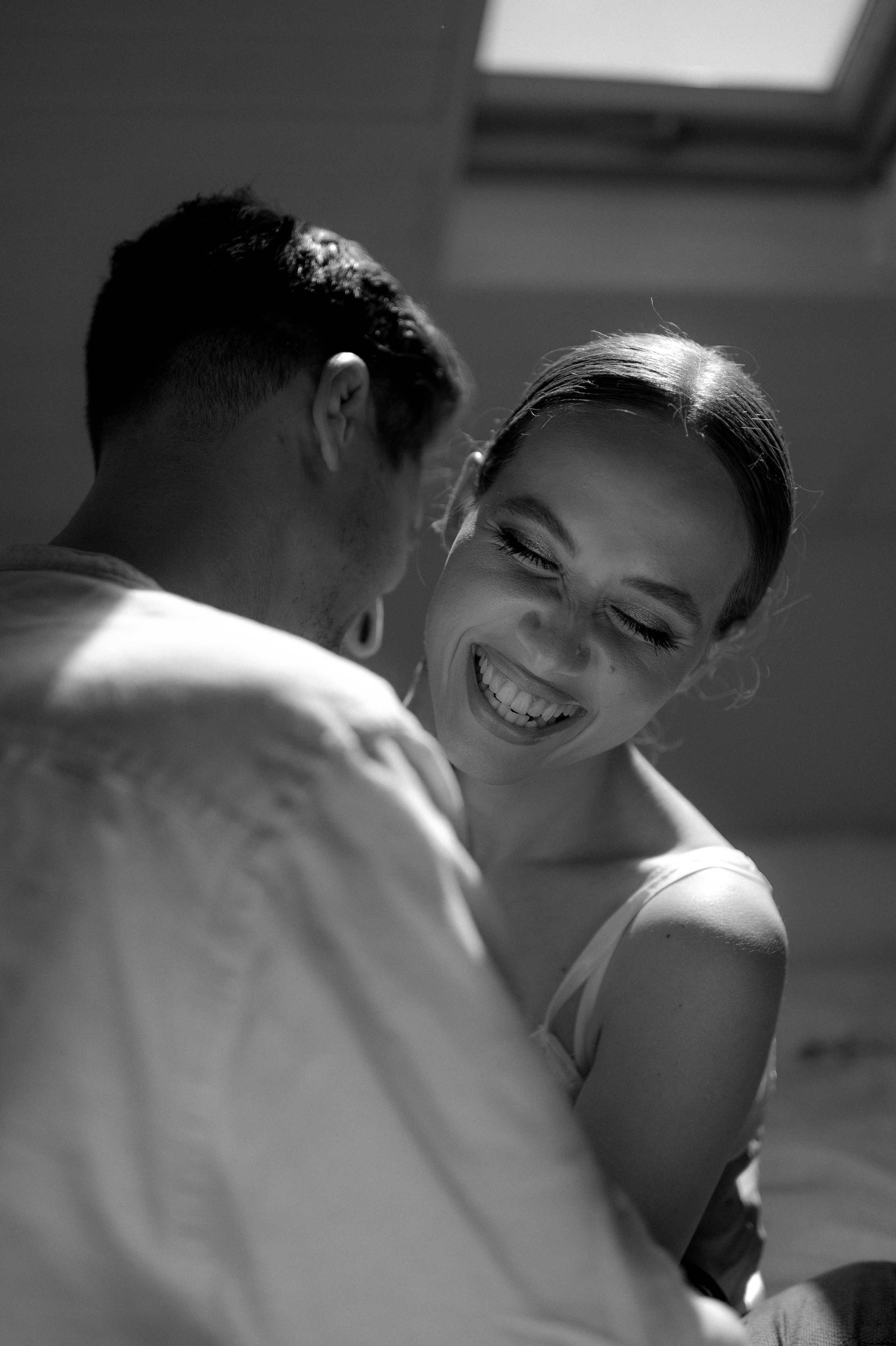Laughter fills the room as the couple shares a playful and lighthearted kiss, their love shining through their infectious smiles.