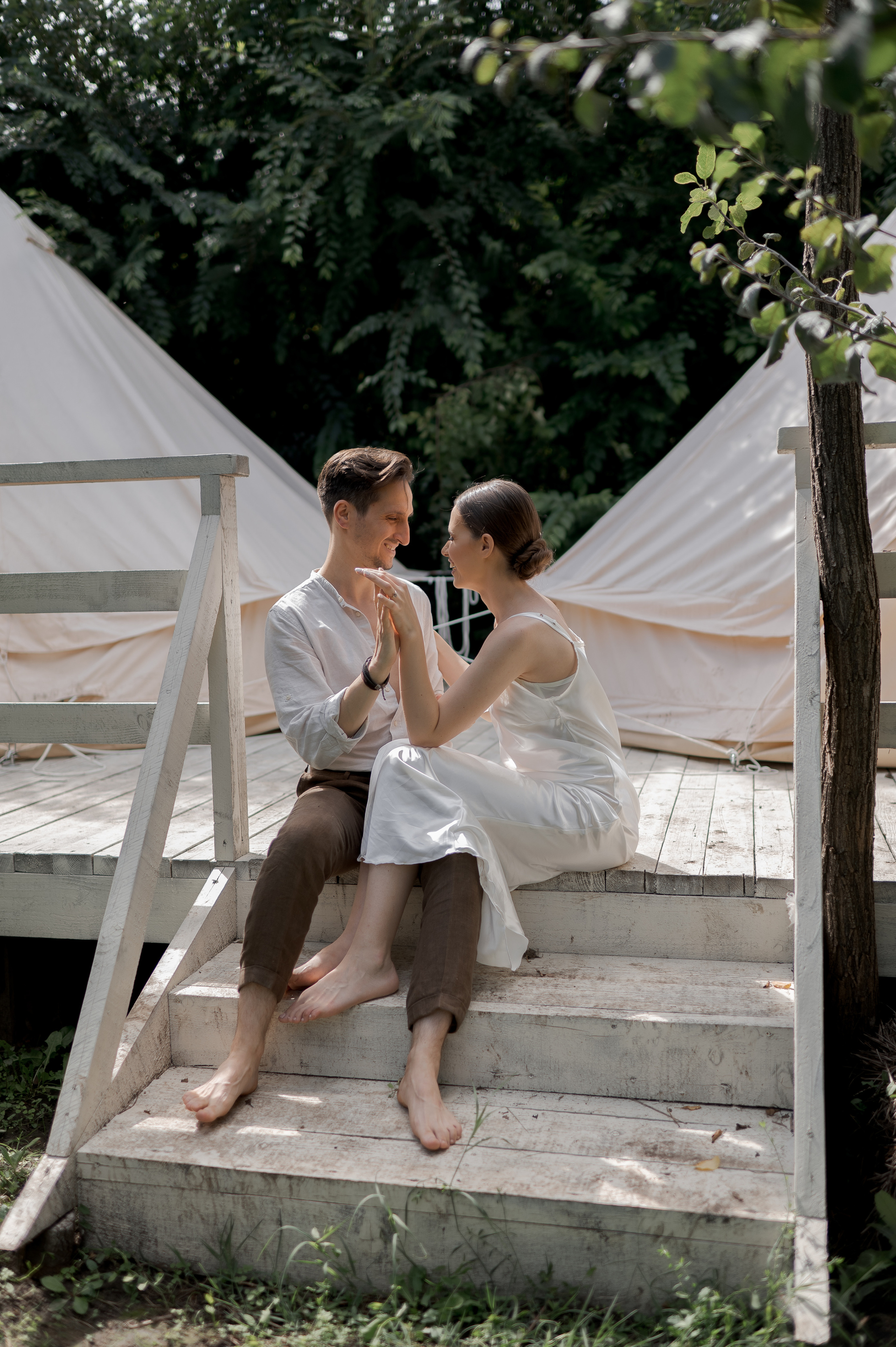 In a secluded garden oasis, the couple awakens to their wedding morning, embraced by the intimacy of glamping tents, sharing loving gazes and tender moments.