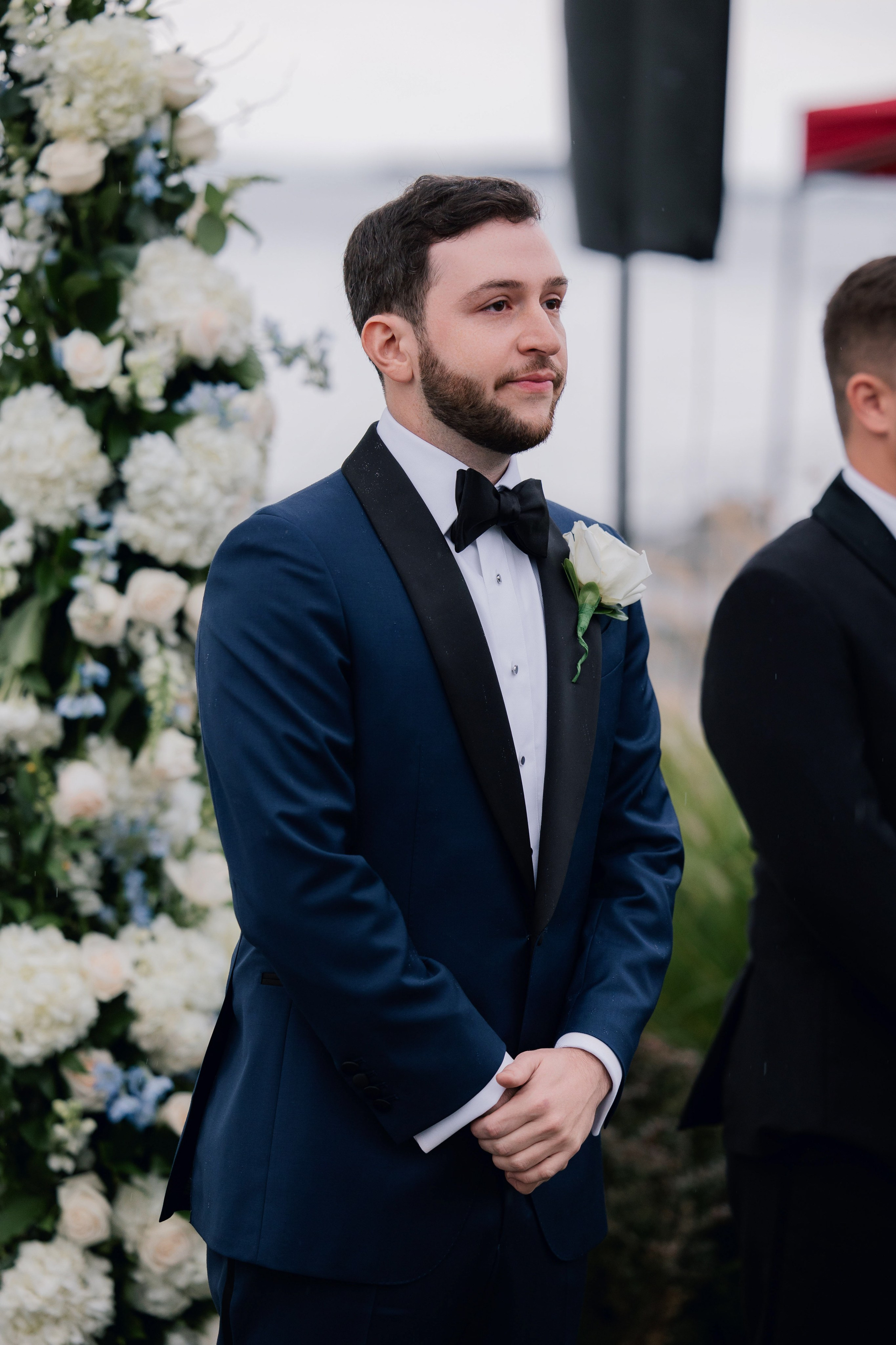 a man in a suit and bow tie standing next to a flower