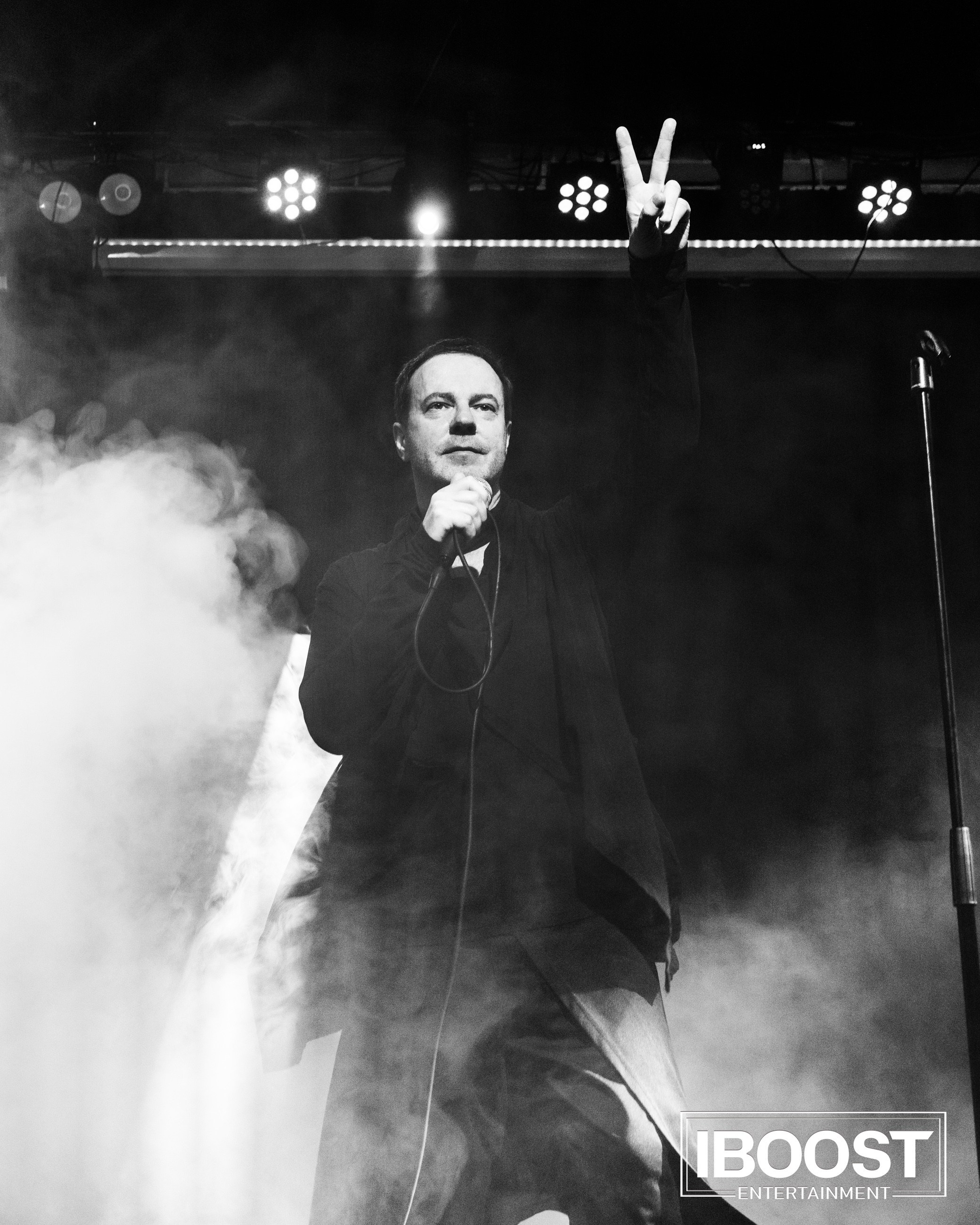 Black-and-white full-body stage photo of the lead vocalist of Animal JazZ performing in dramatic smoke and light.