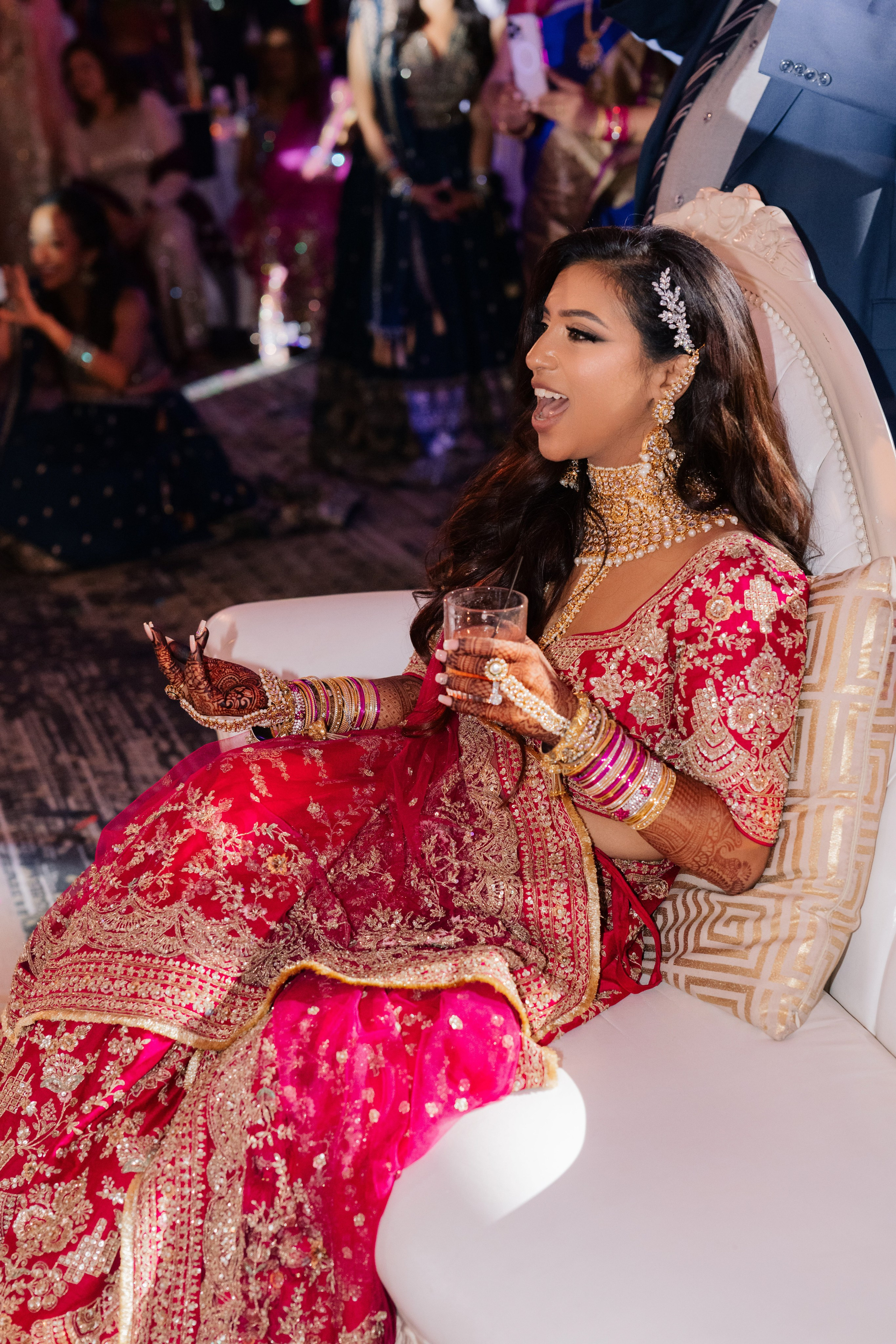 a woman in a red and gold dress sitting on a white chair