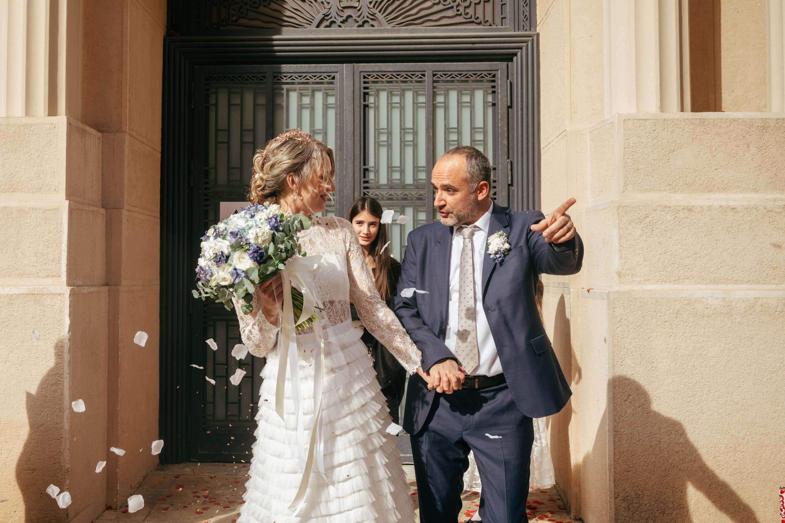 Les mariés sortent de la mairie pendant que les invités jettent des confettis.
