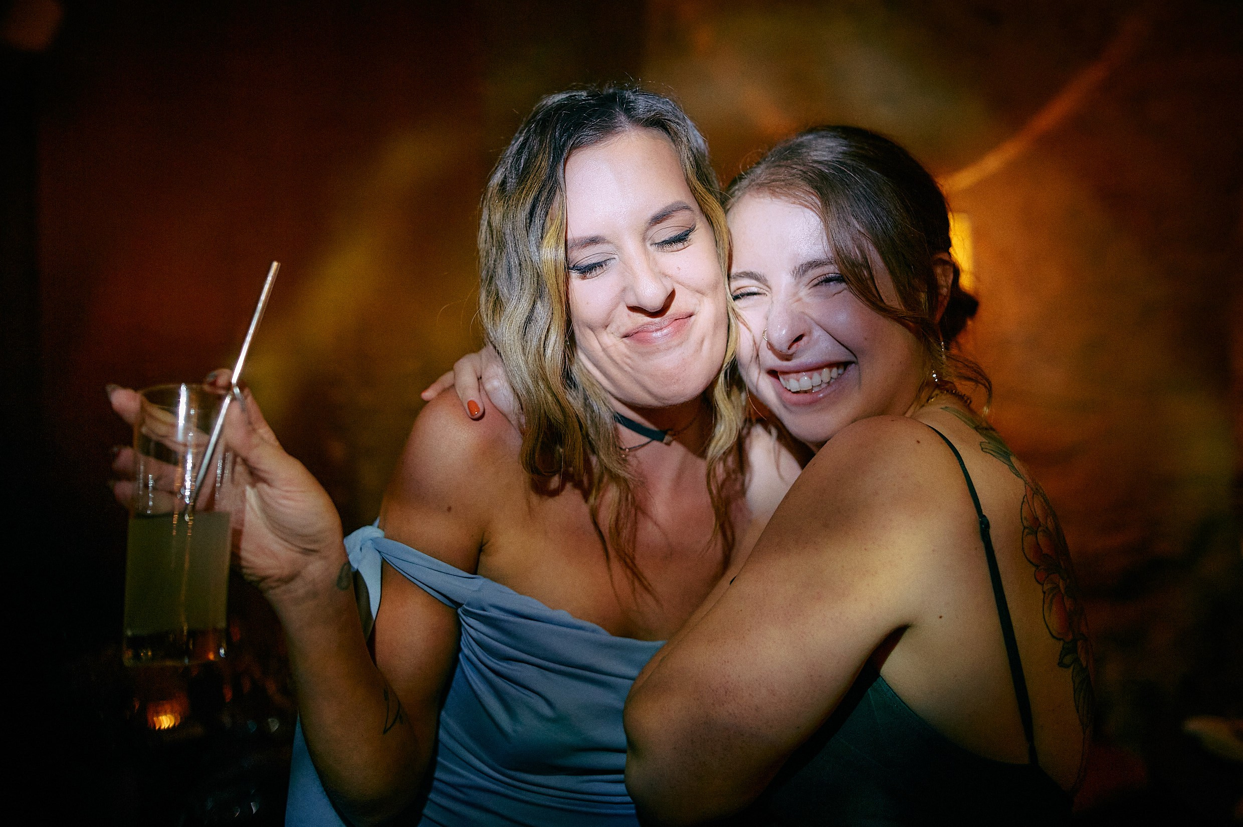 Guests hugging with drinks at reception.