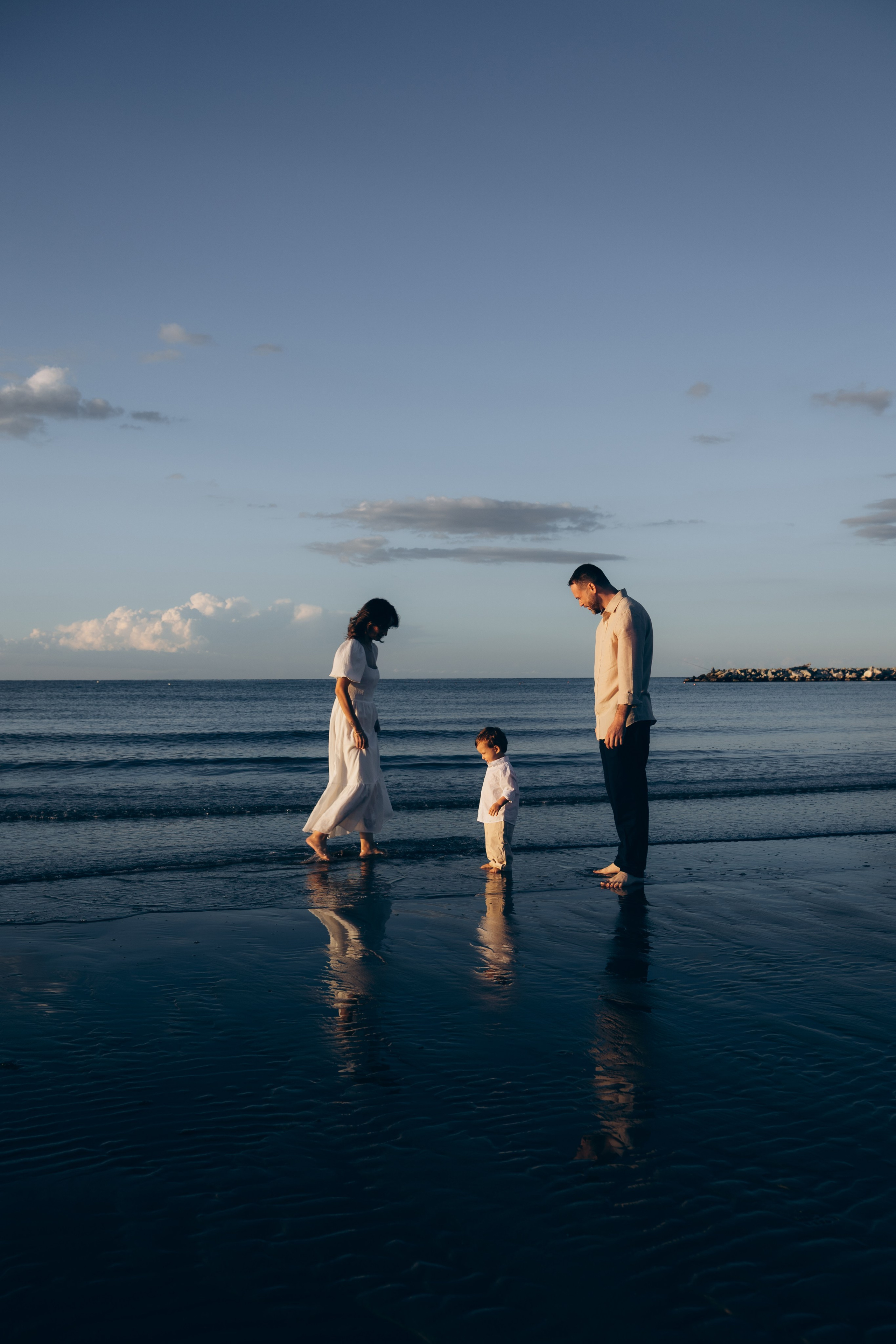 Famiglia con bambino e riflessi sull’acqua al tramonto sulla spiaggia di Rimini.