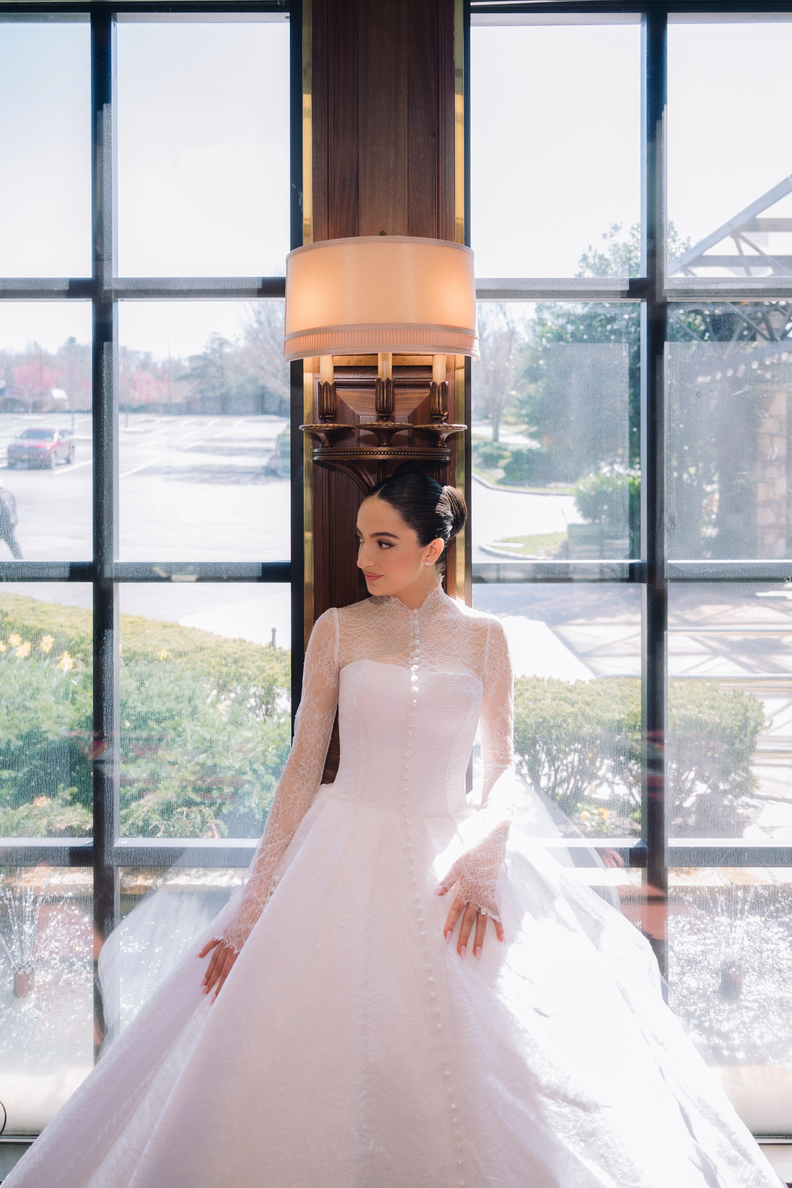 a woman in a white wedding dress standing in front of a window