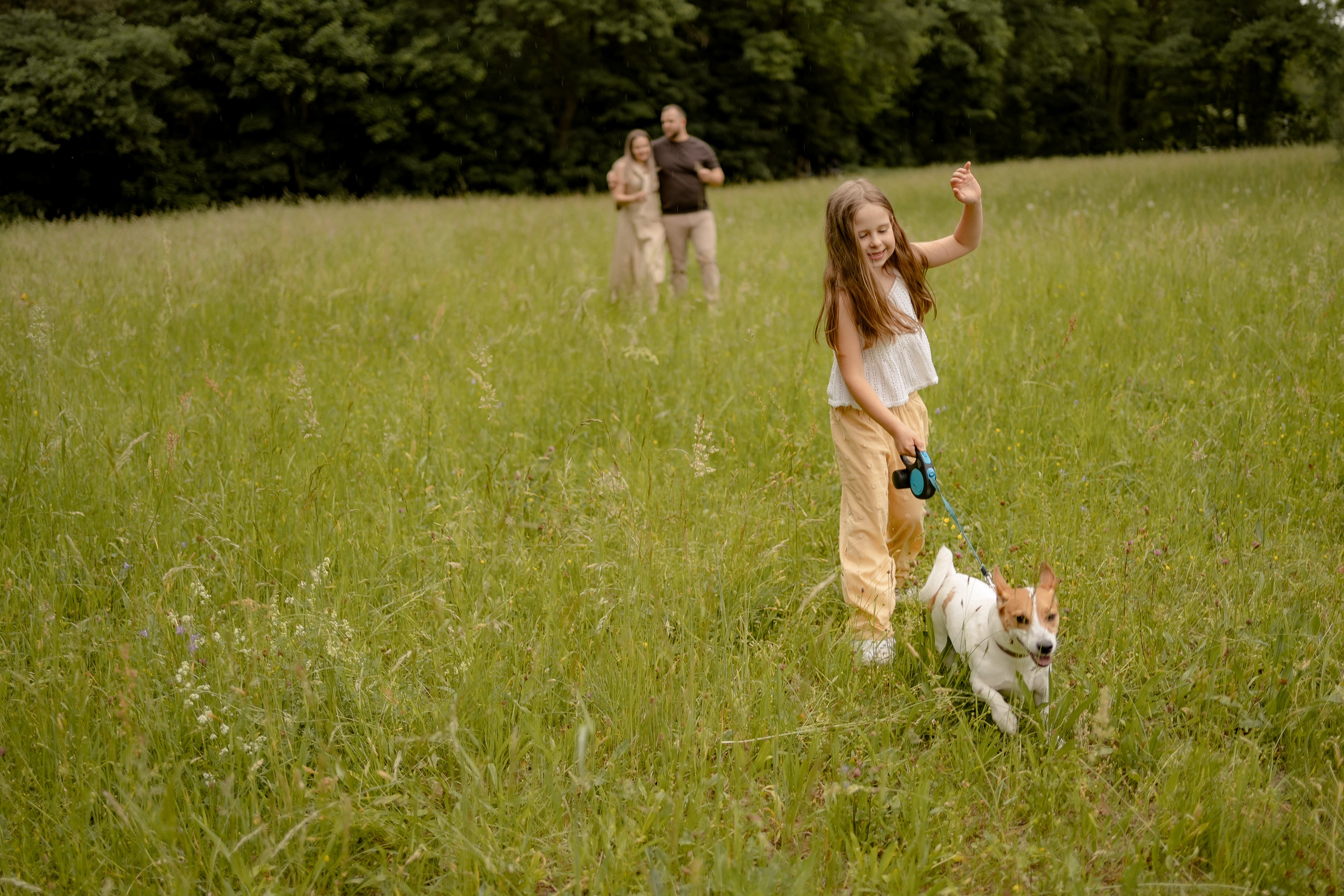 Mädchen läuft mit dem Familienhund über eine sommerliche Wiese.