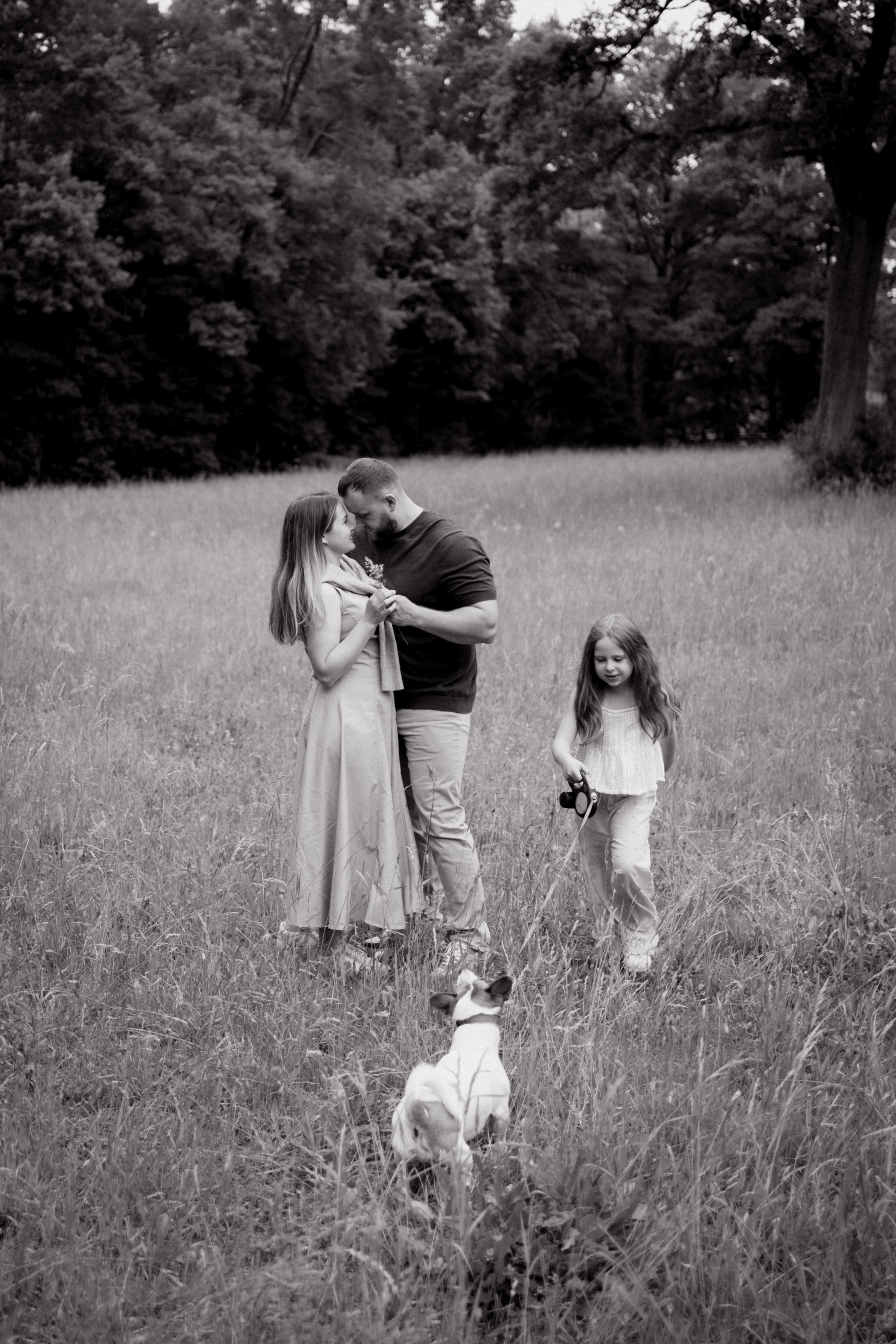 Schwarz-Weiß-Foto einer Familie mit Hund beim gemeinsamen Spaziergang.