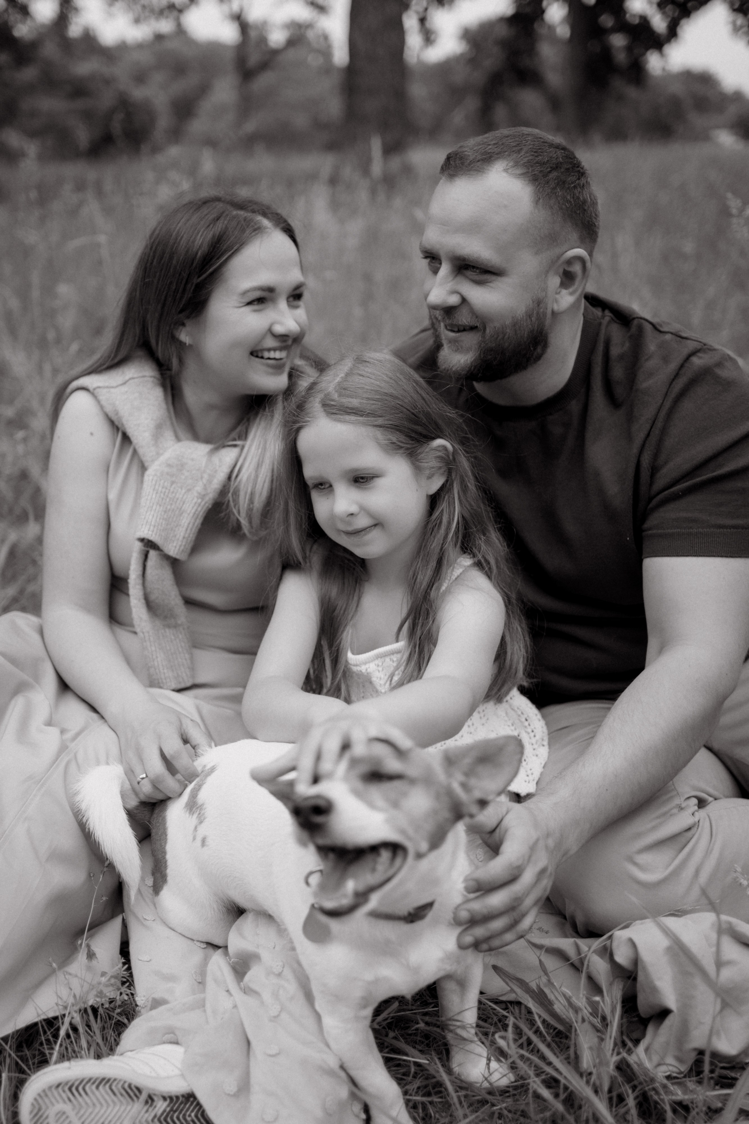 Schwarz-Weiß-Familienportrait von Mutter, Vater und Tochter mit ihrem Hund.